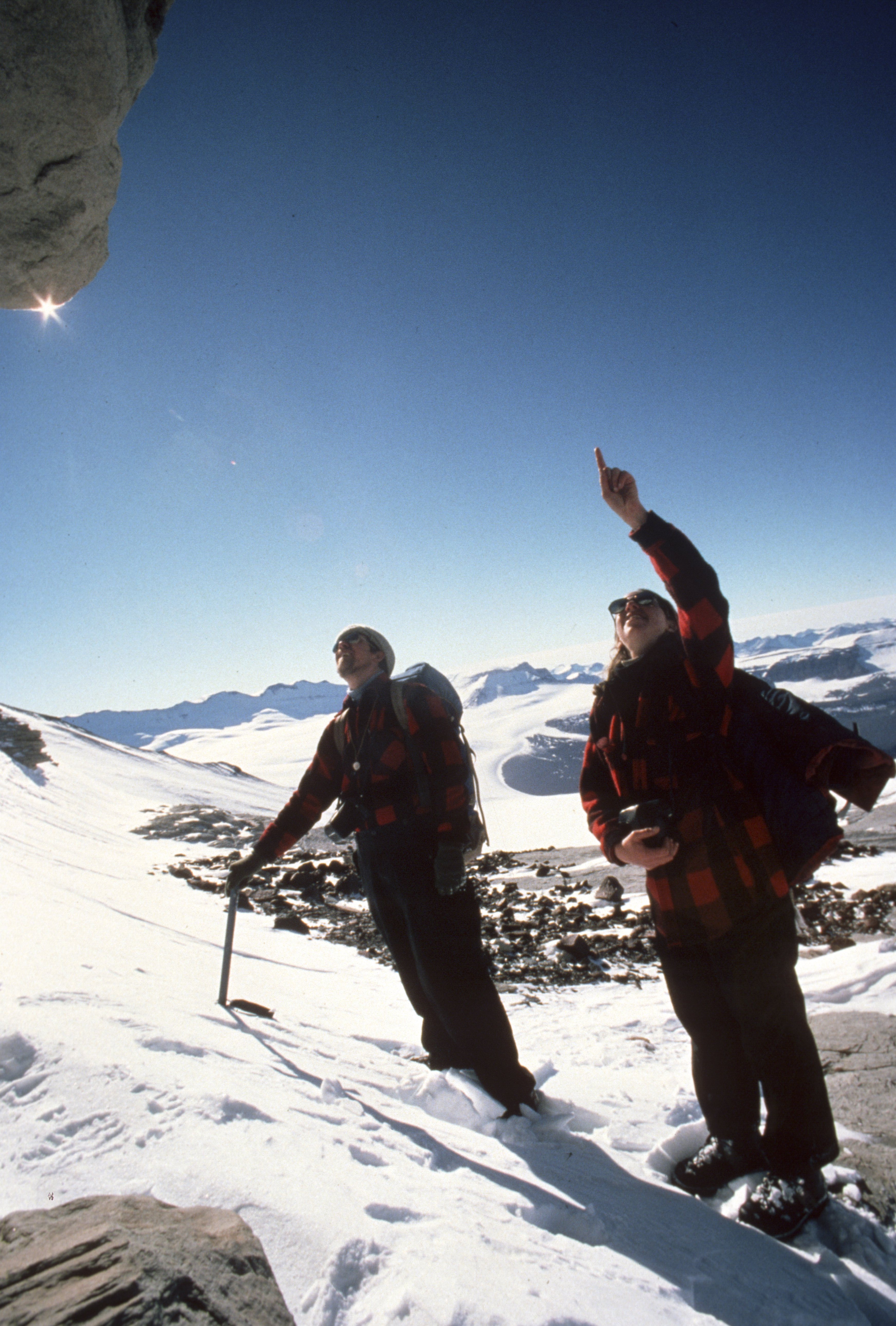 Two people stand on a mountainside.