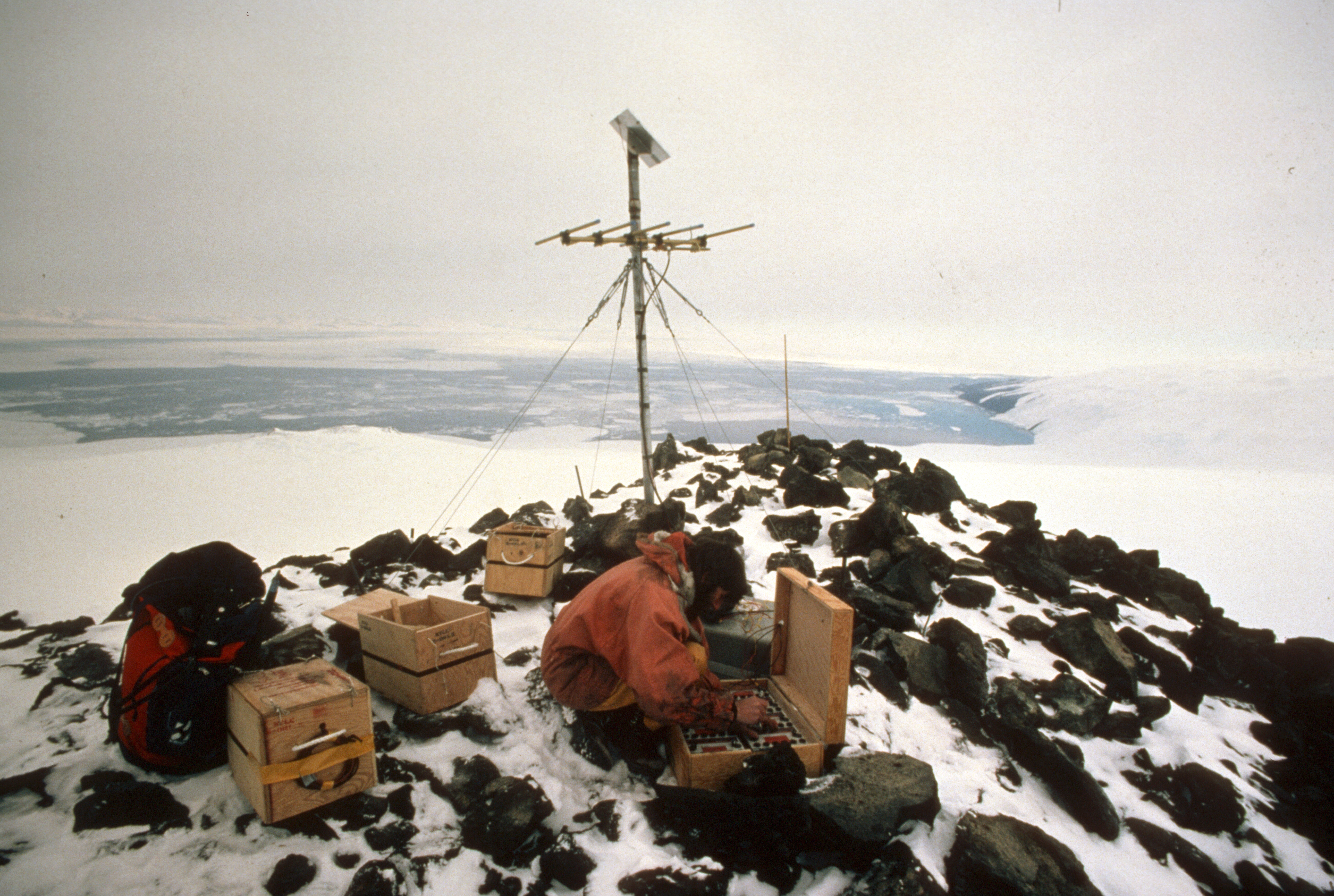 A person working with an antenna on top of a mountain.