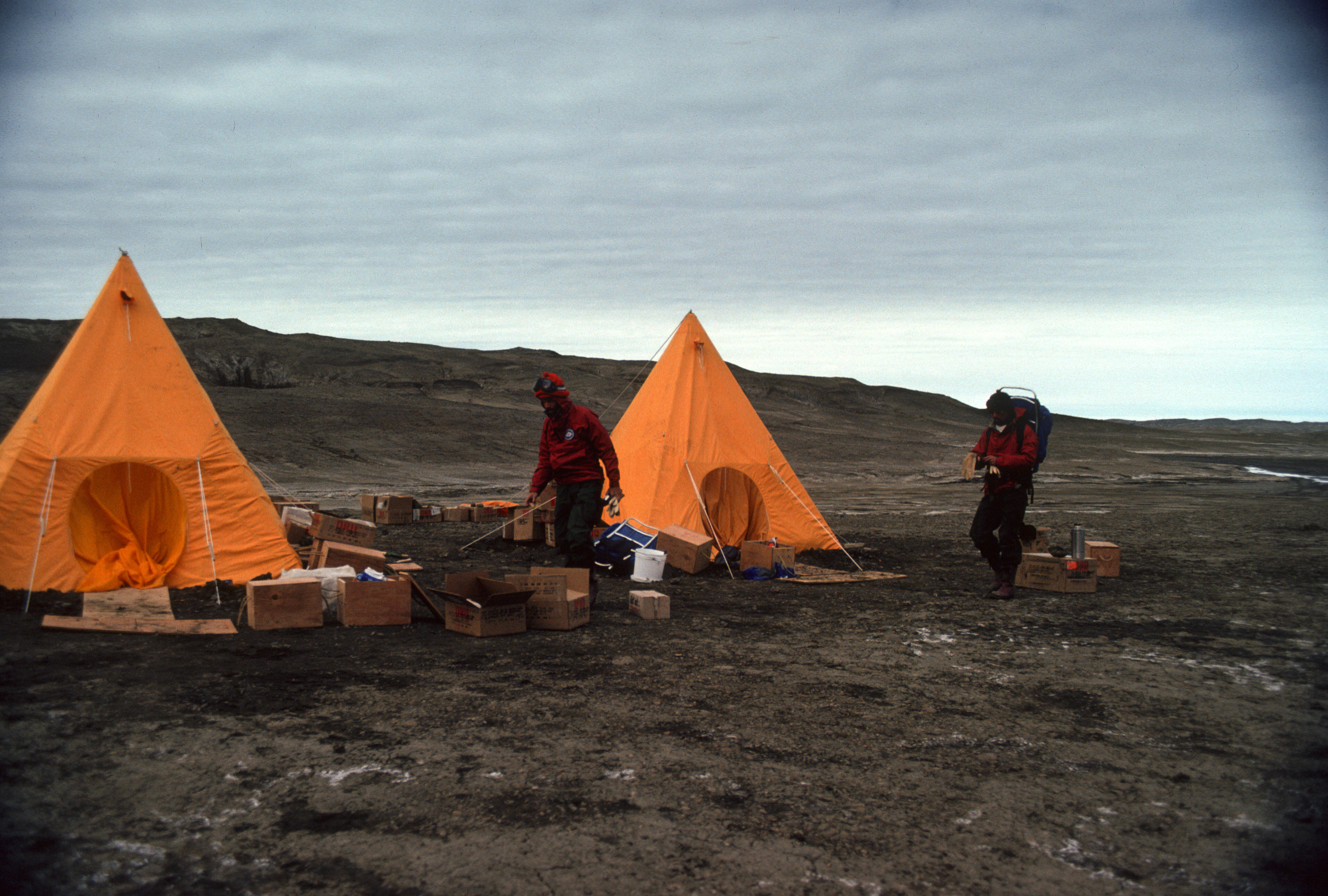 Two yellow pyramid-shaped tents on rocky terrain.