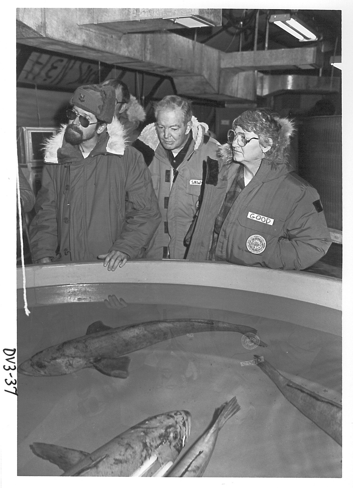 Four people standing next to an aquarium tank.