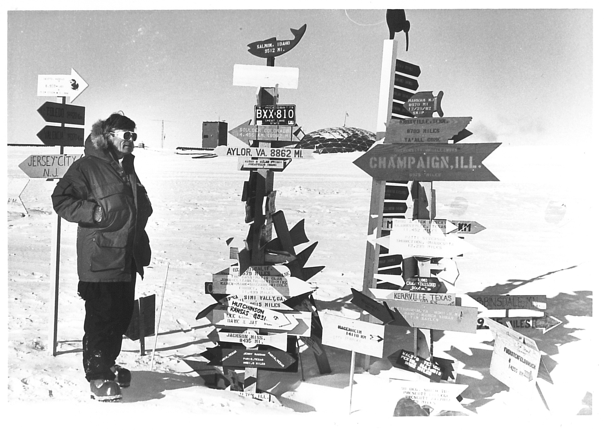 A man standing next to a large collection of directional signs.