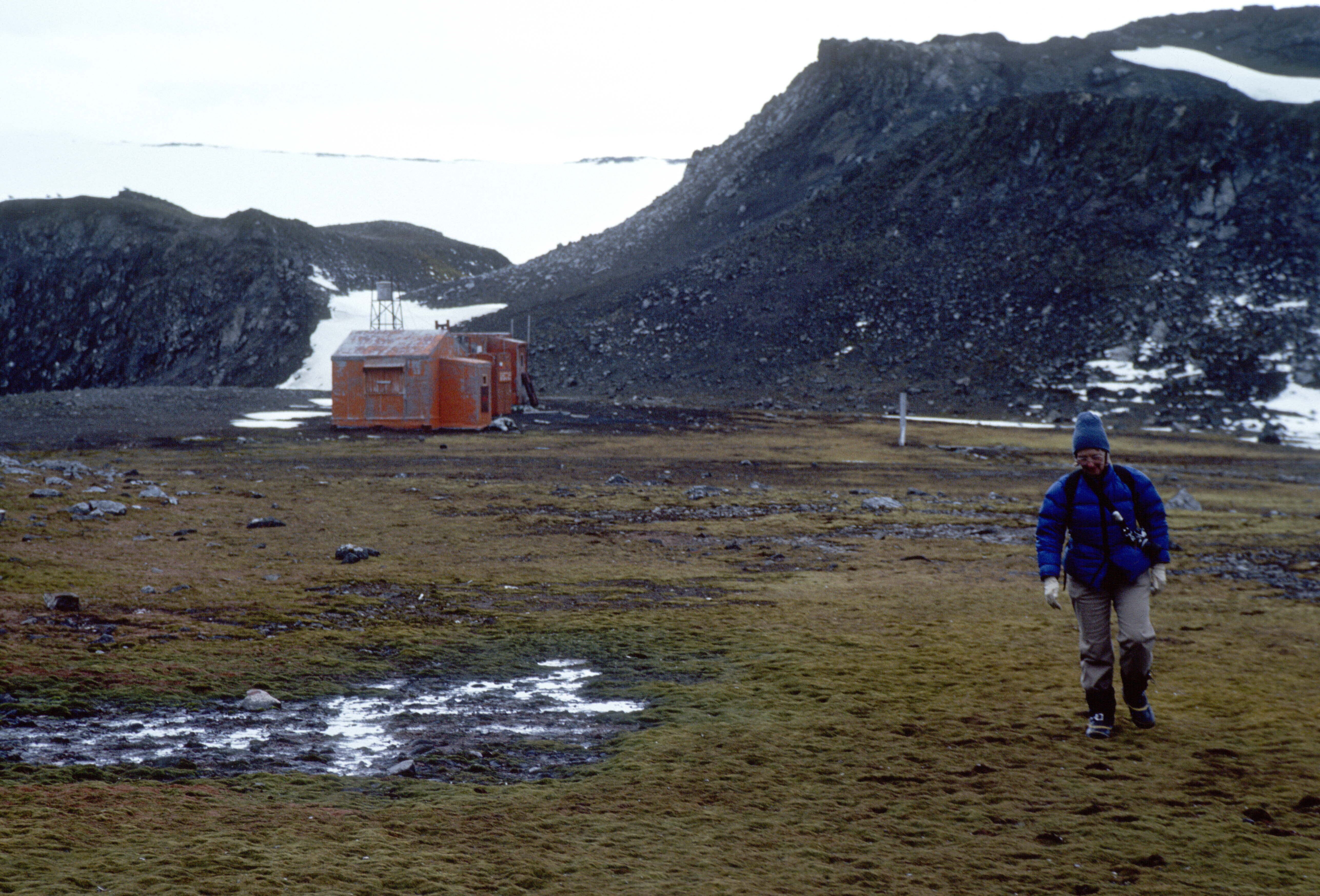 A person walking towards the camera with a building in the far distance.