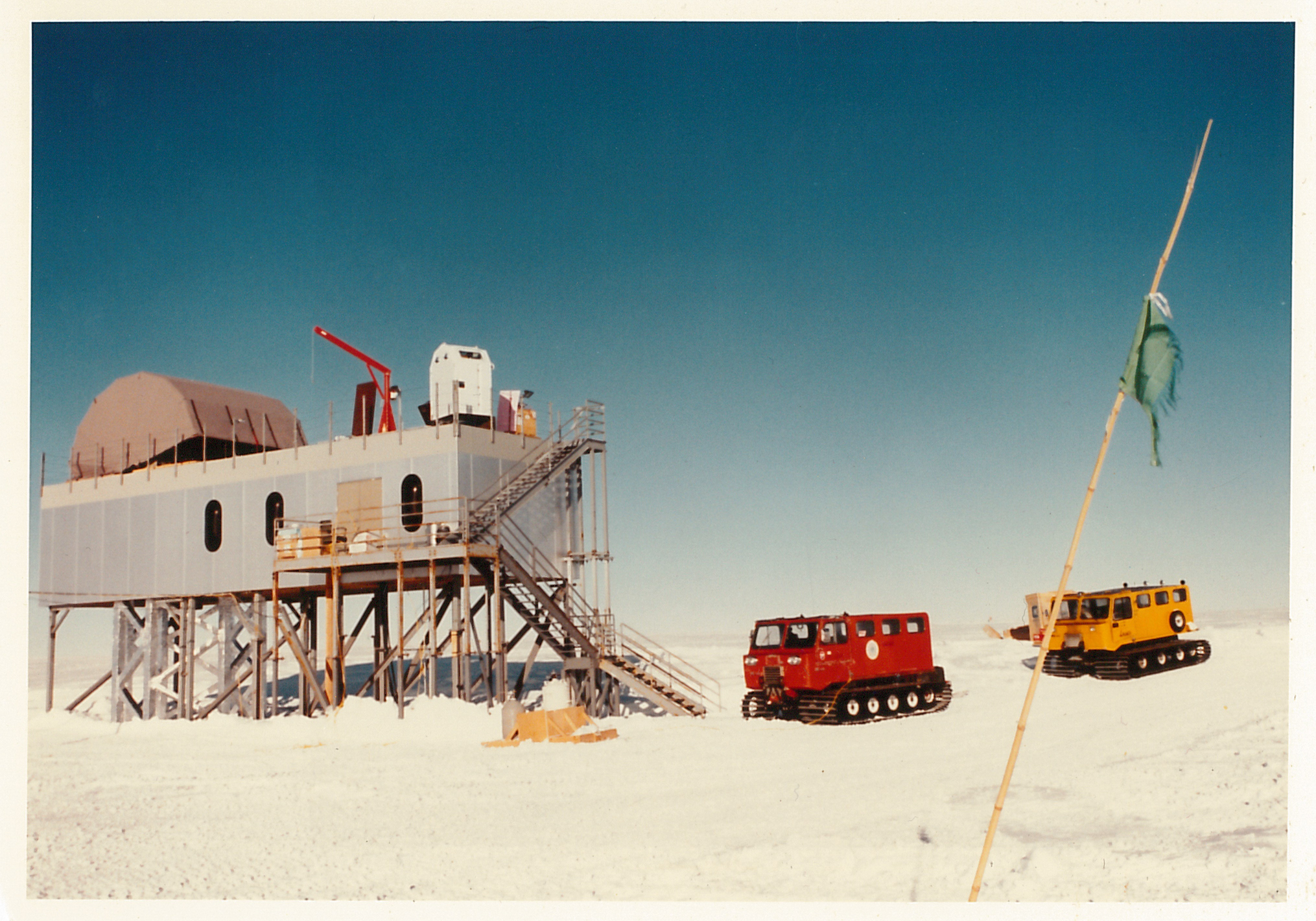 An elevated building and two tractors on the snow.