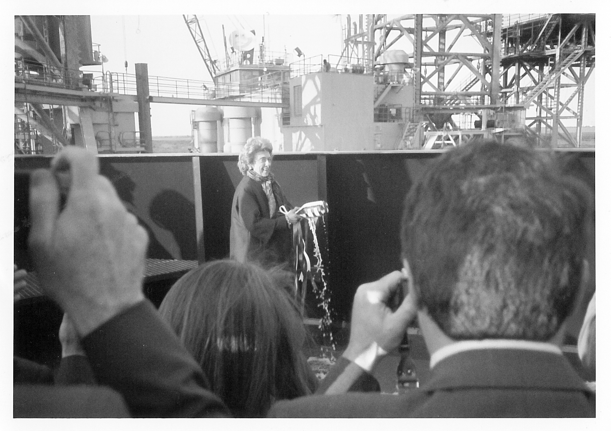 A woman breaking a champagne bottle over a ship.