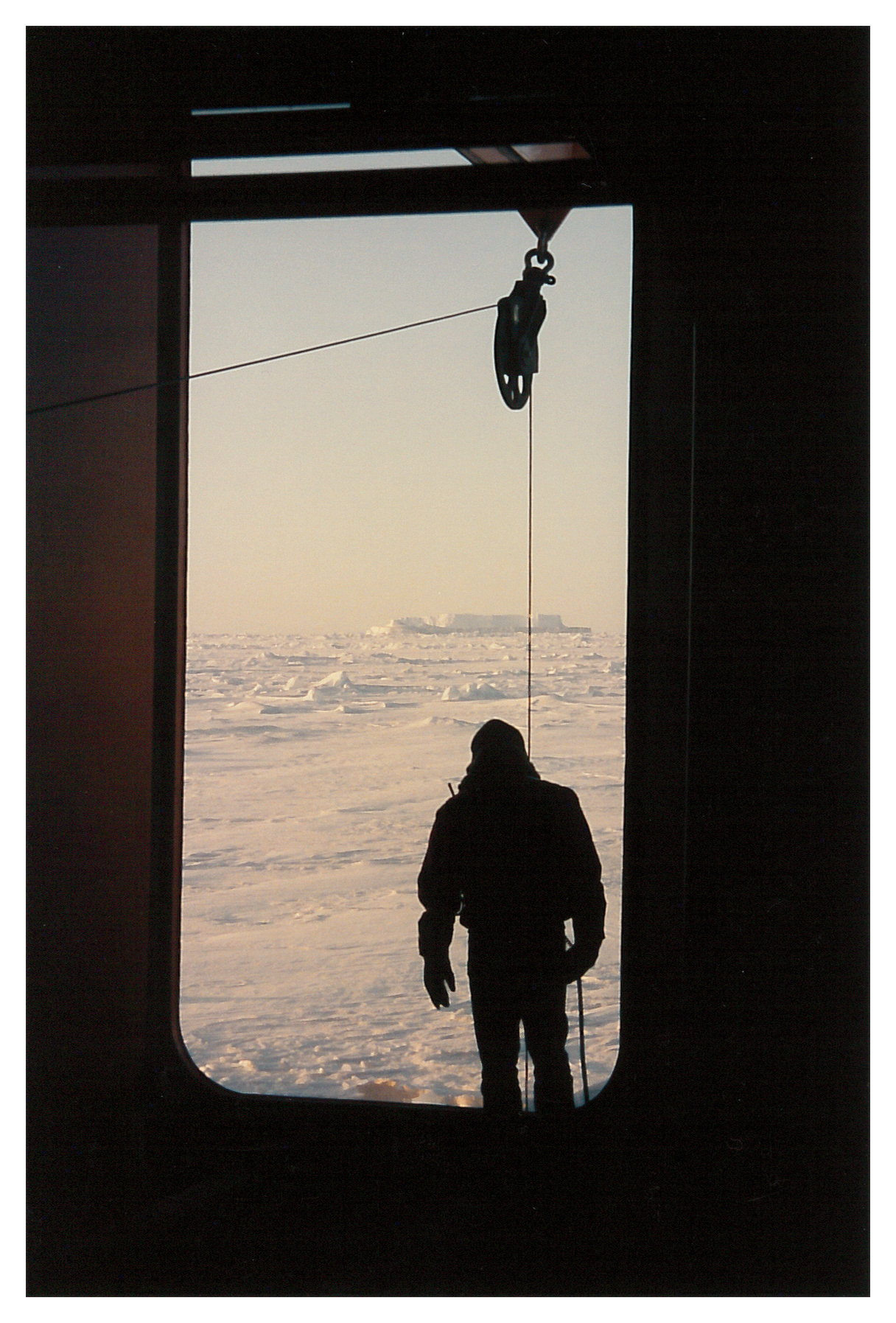 A person standing in an open port door of a ship.