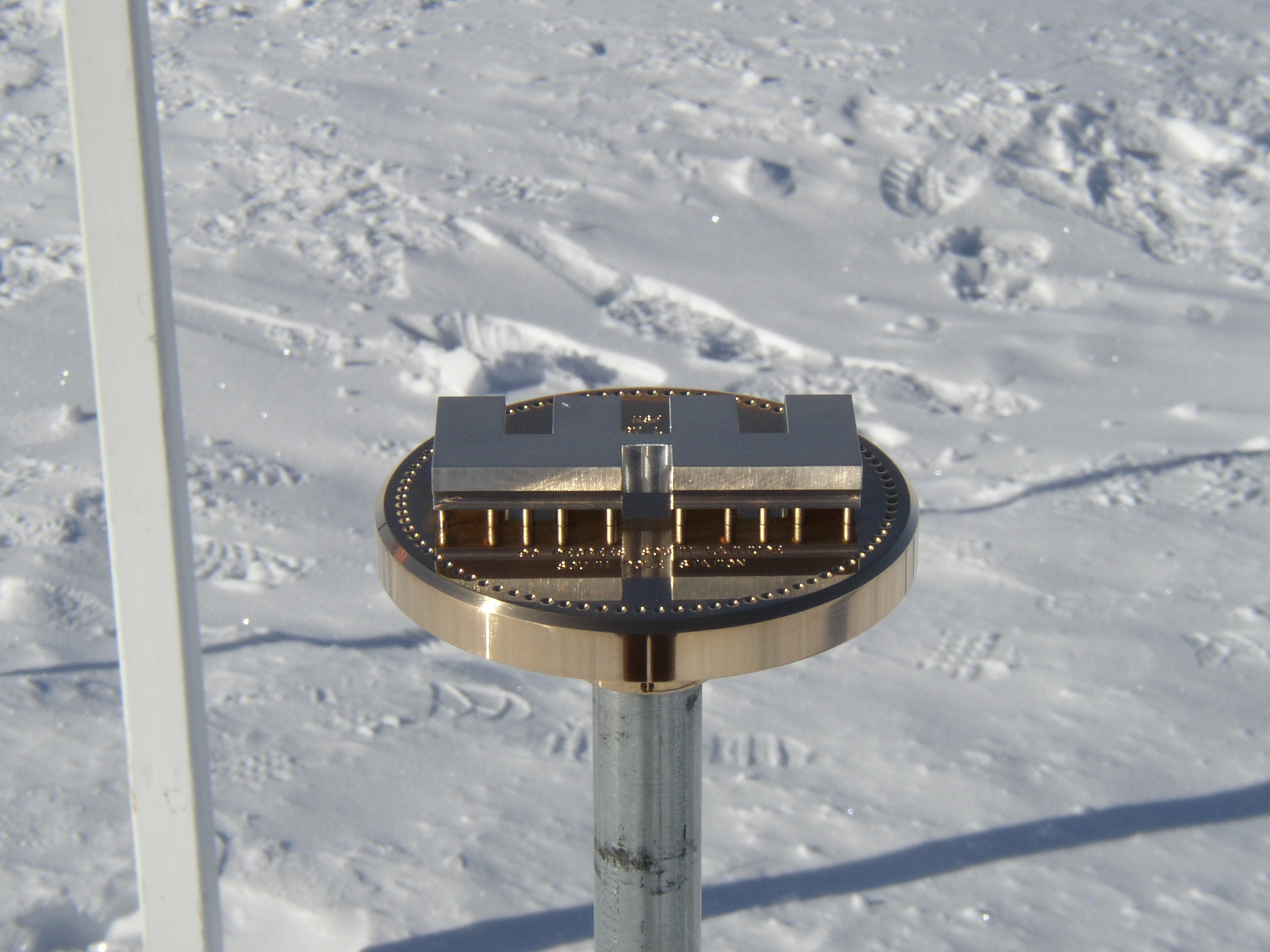 A brass marker on top of a steel pole.