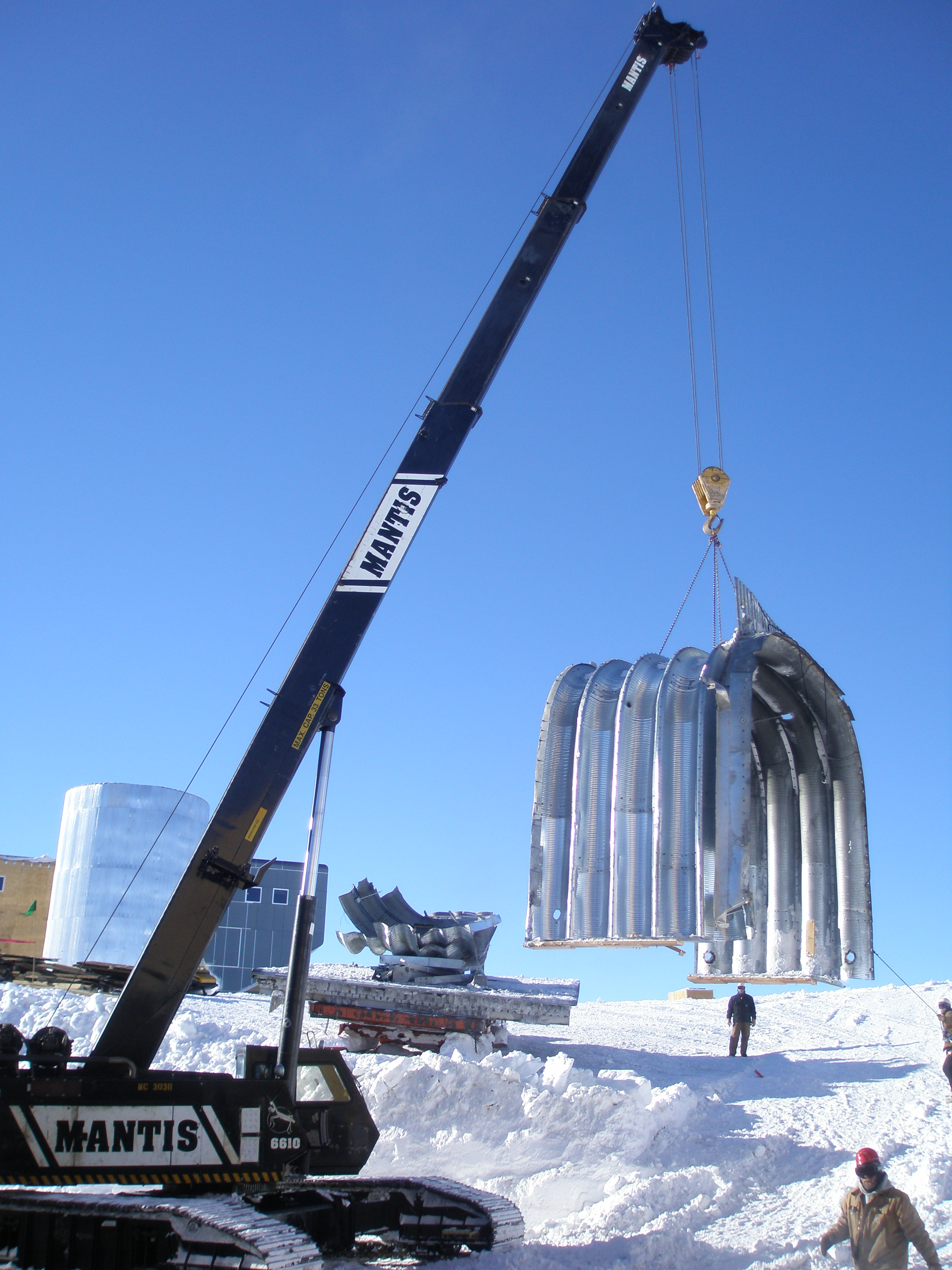 A construction crane lifting a section of an arch.