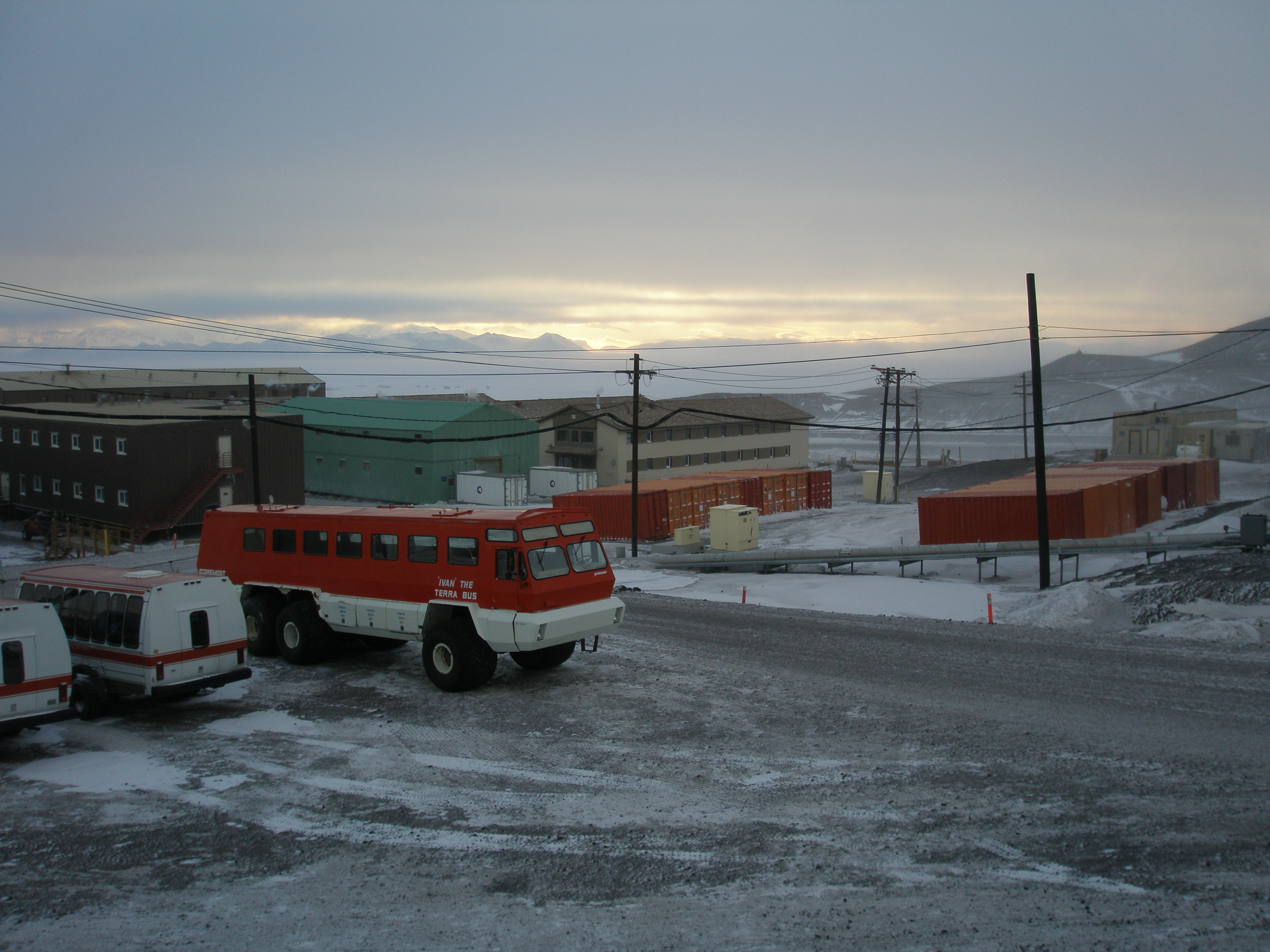 A large bus with buildings and a frozen landscape in the background.