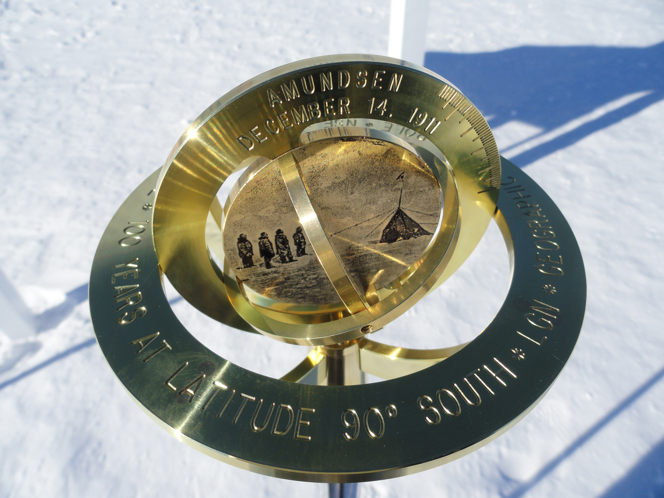 Brass pole marker stands in the snow.