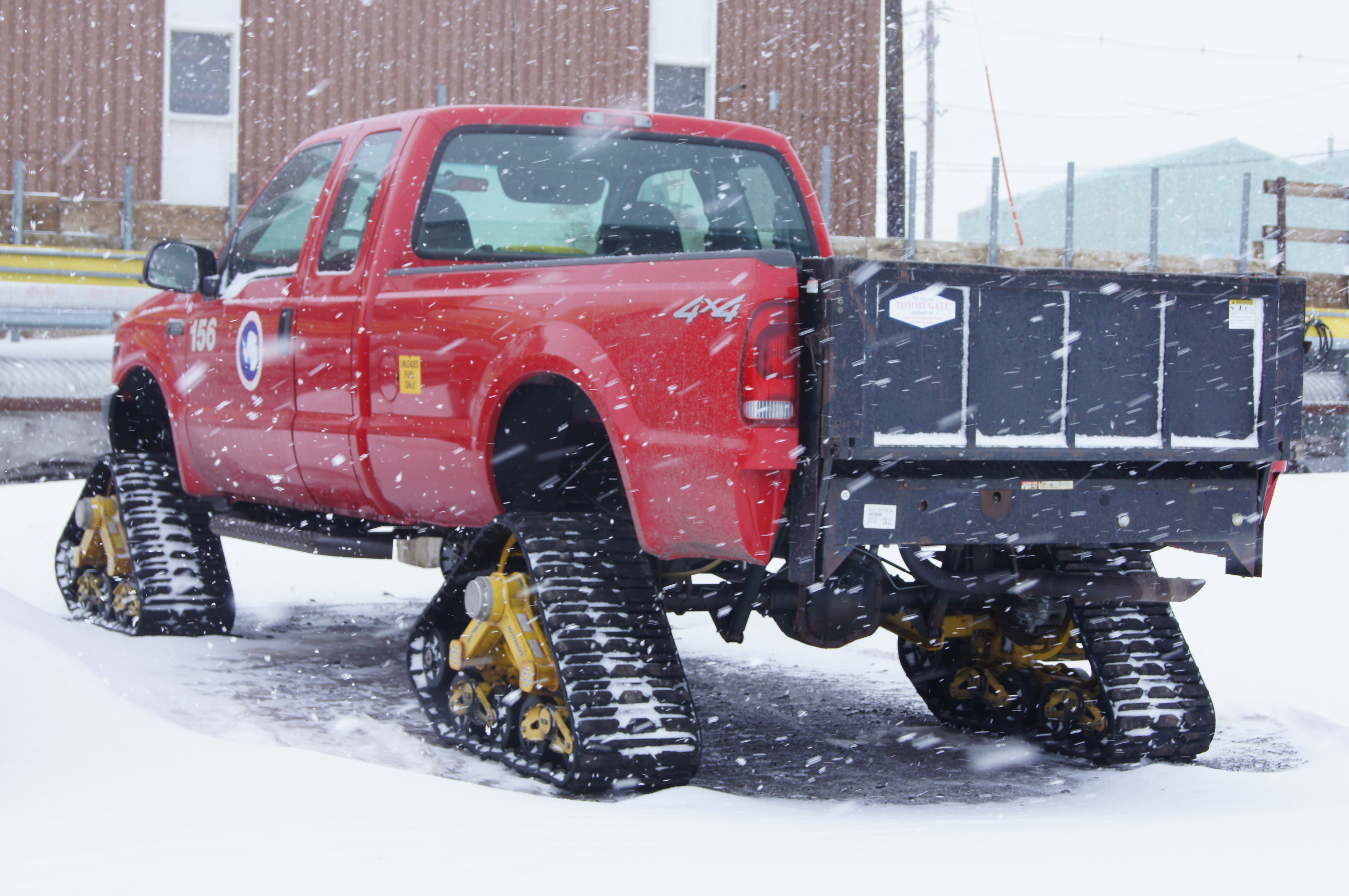 A red truck with tractor treads instead of wheels.