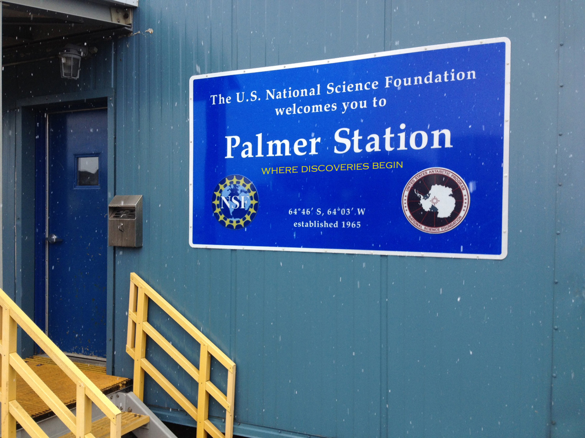 A blue sign that says The U.S. Antarctic Program Welcomes You to Palmer Station.