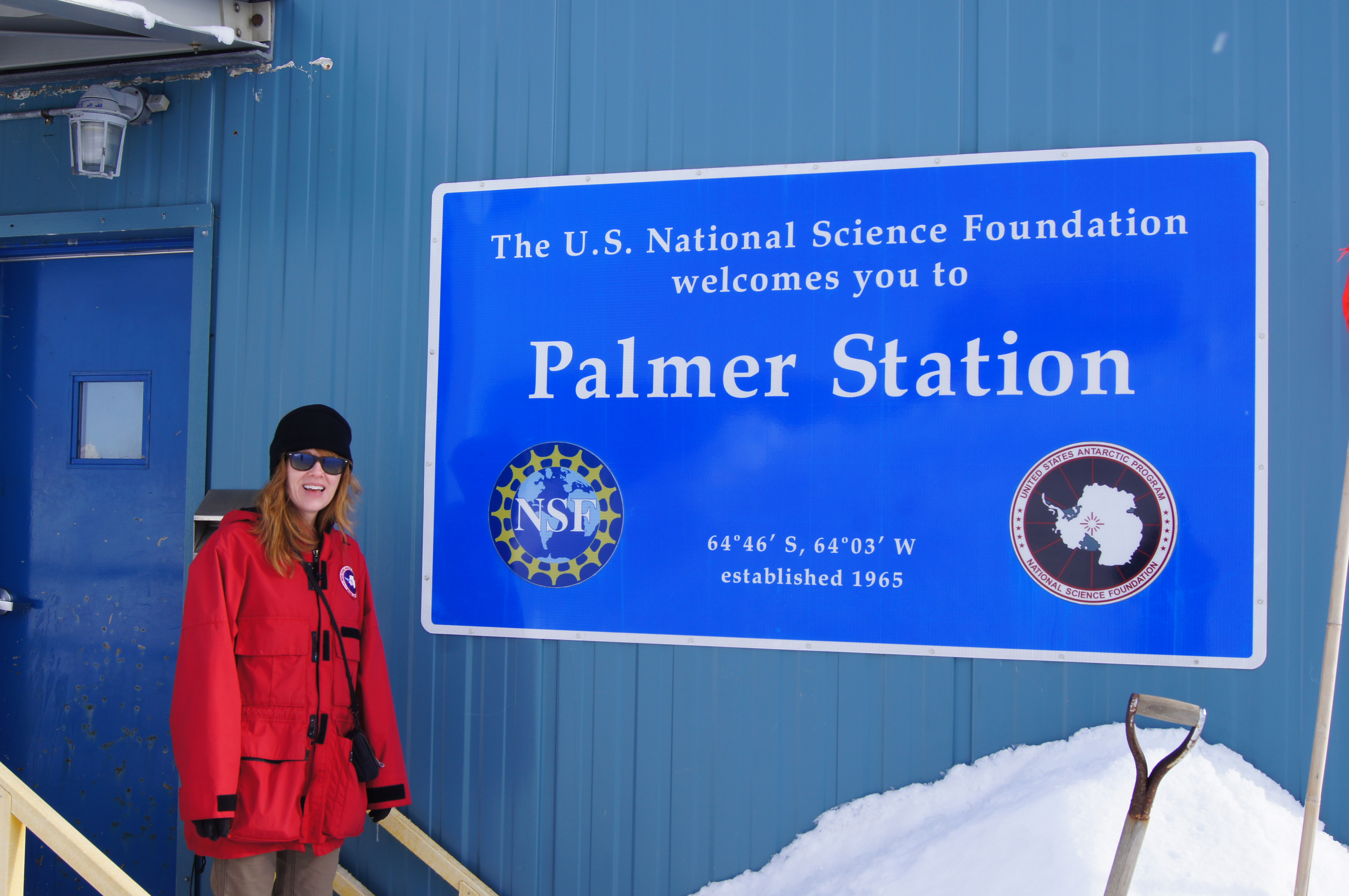 A woman standing by a large sign.