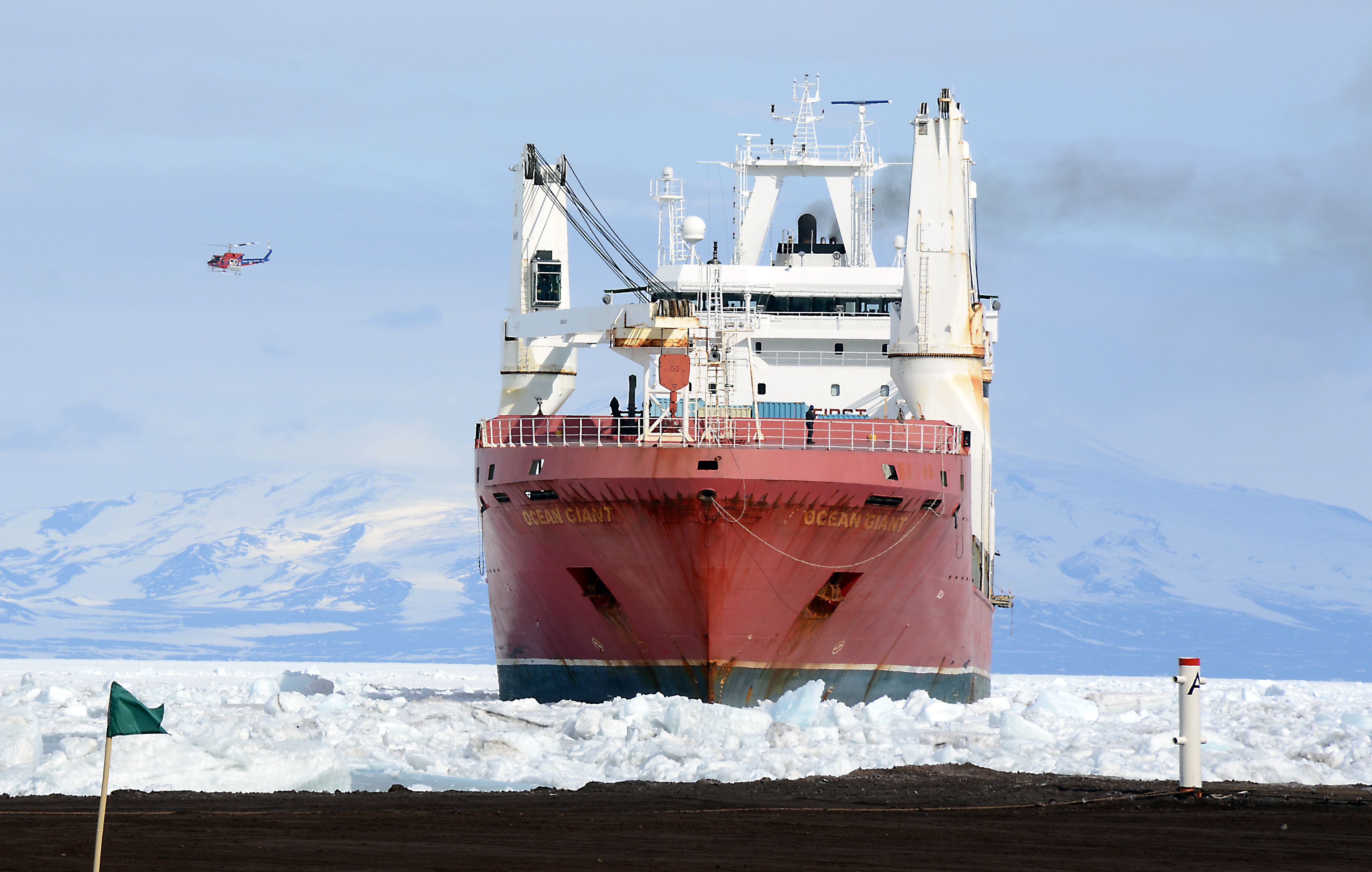 A helicopter passes over a ship.