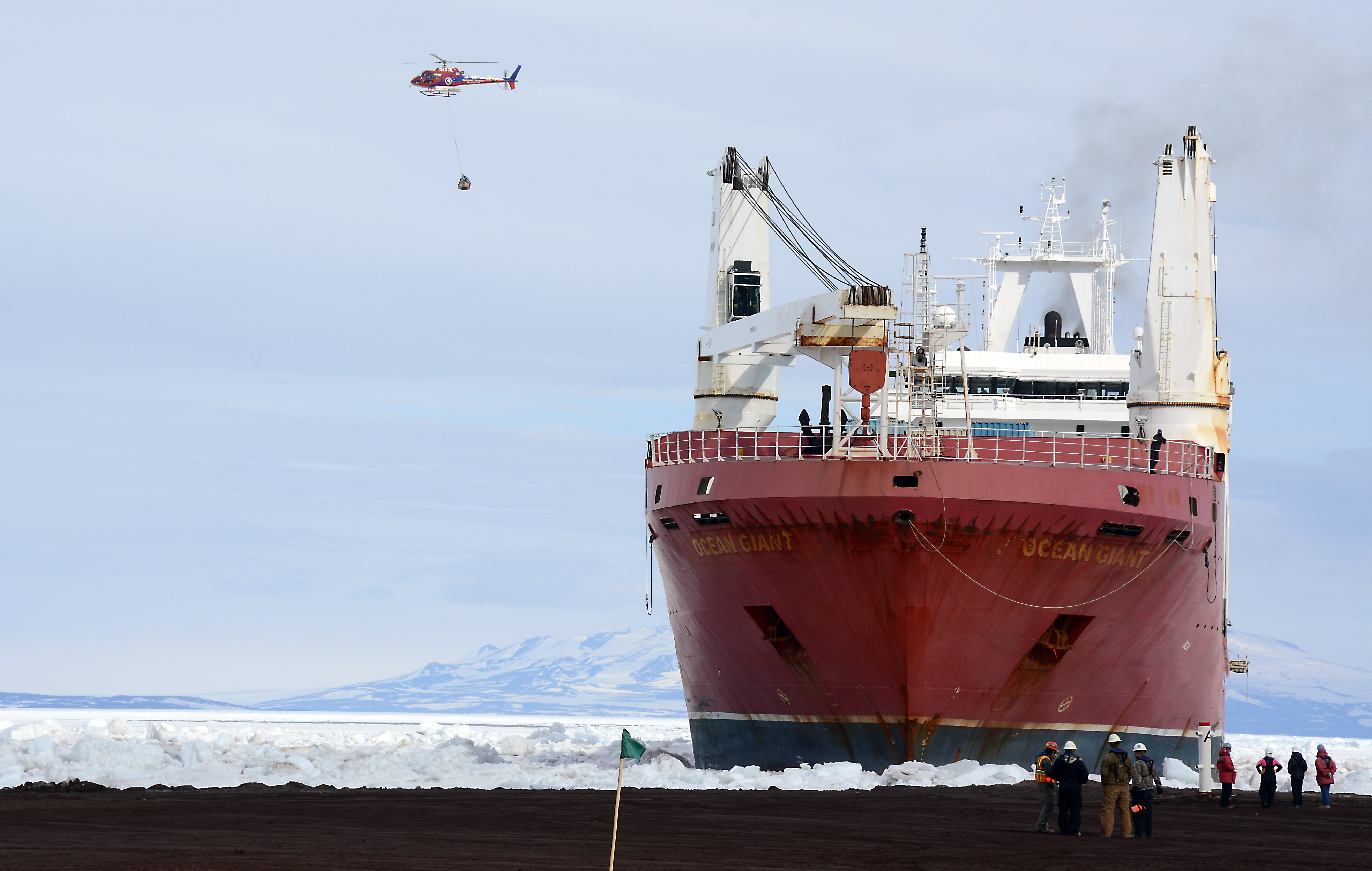 A helicopter passes over a ship.