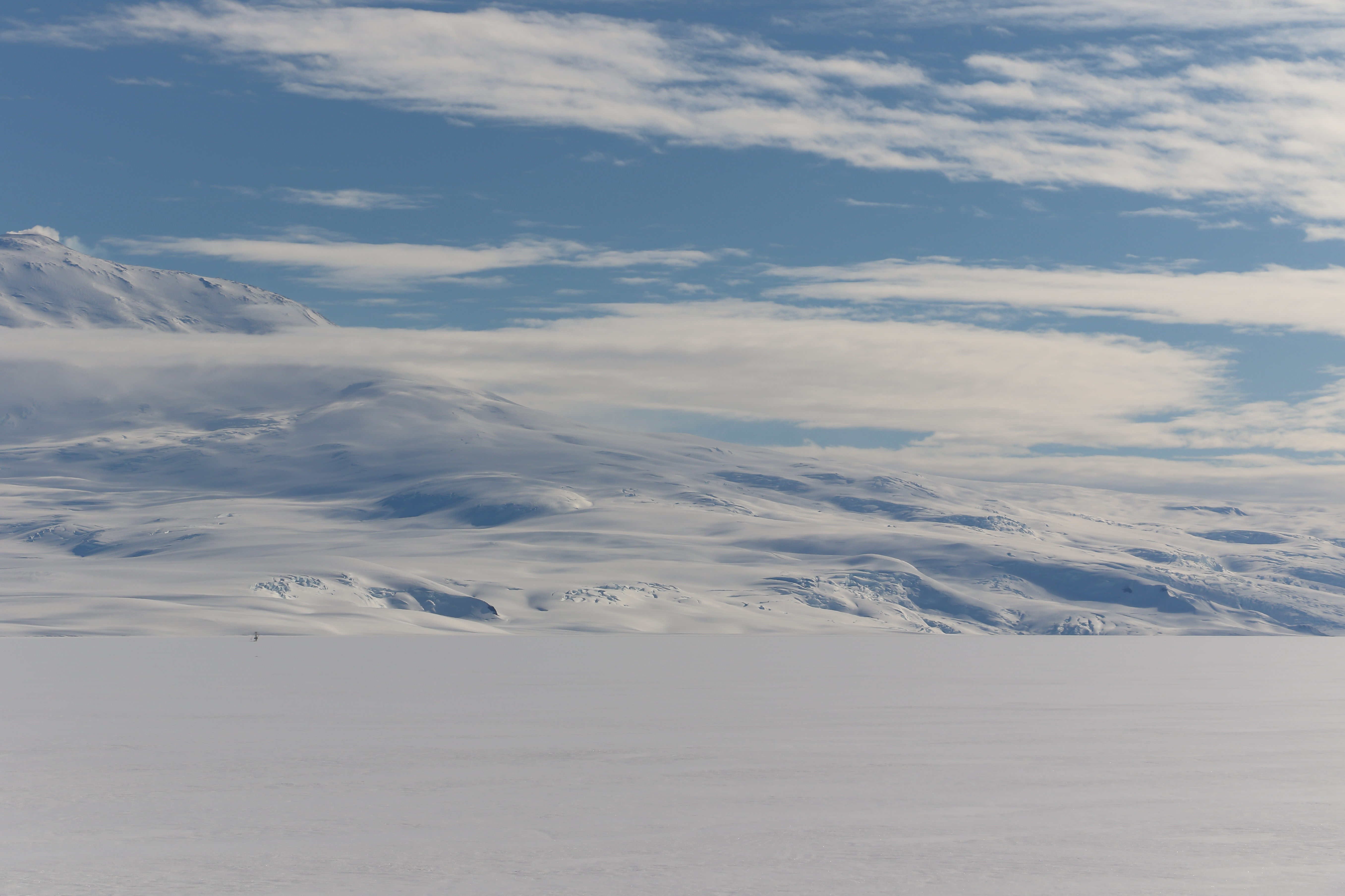 A partly cloudy sky over snow-covered landscape.