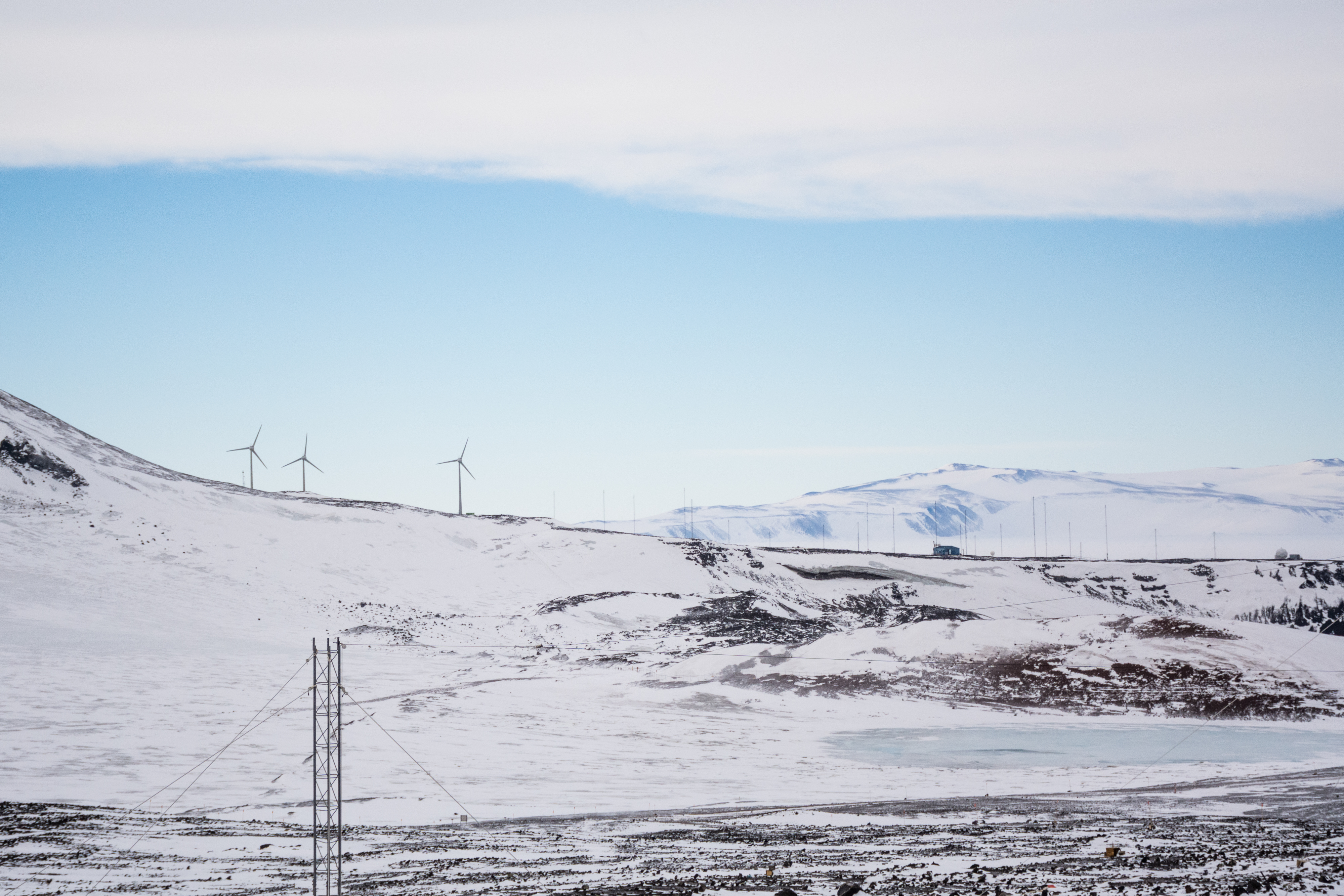 A snow-dusted landscape with wind turbines in the distance.