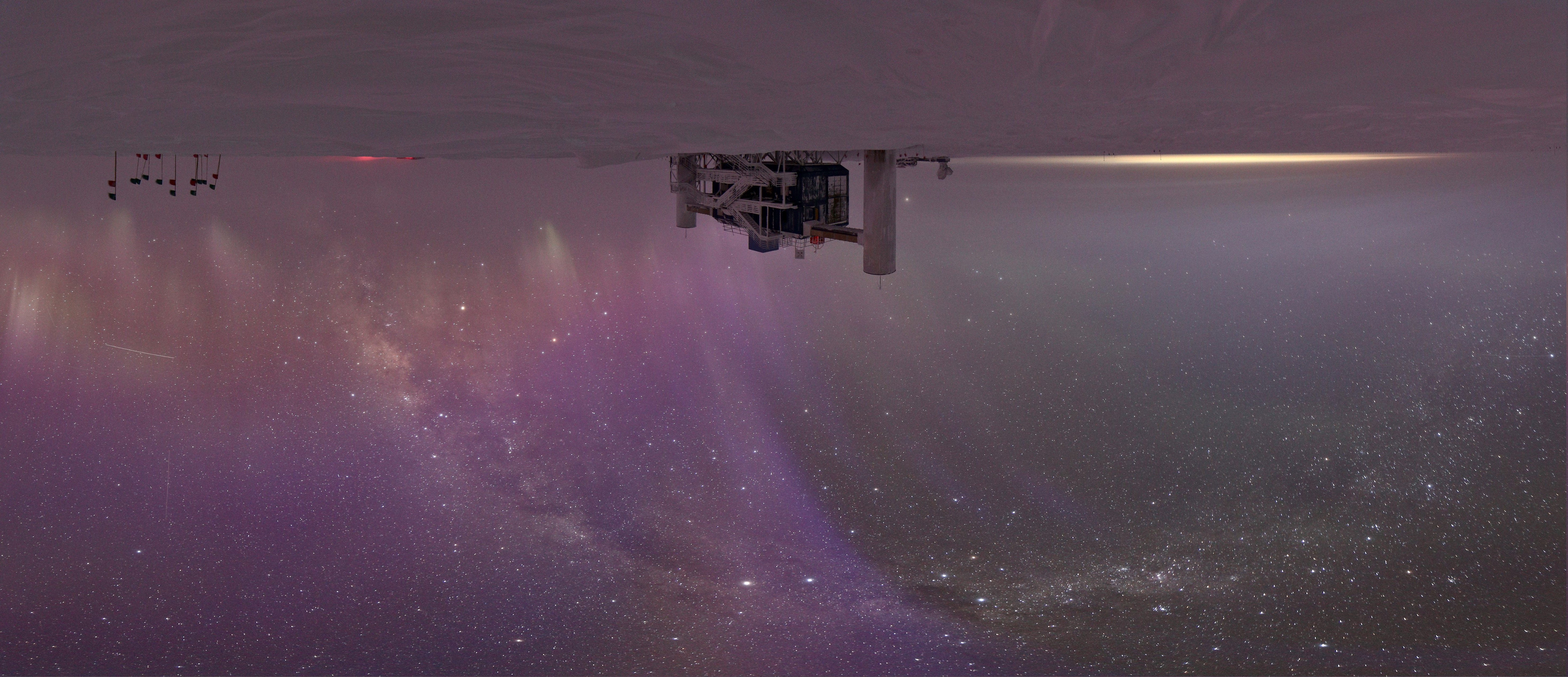 The Milky Way and Auroras in the night sky over a building.