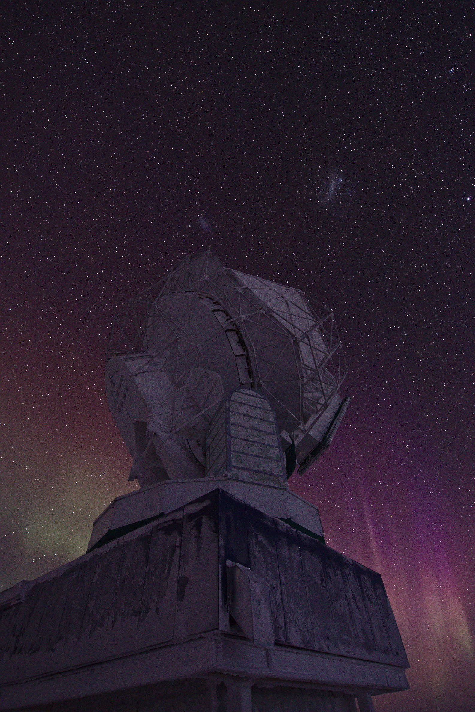 Auroras in the night sky over a telescope.