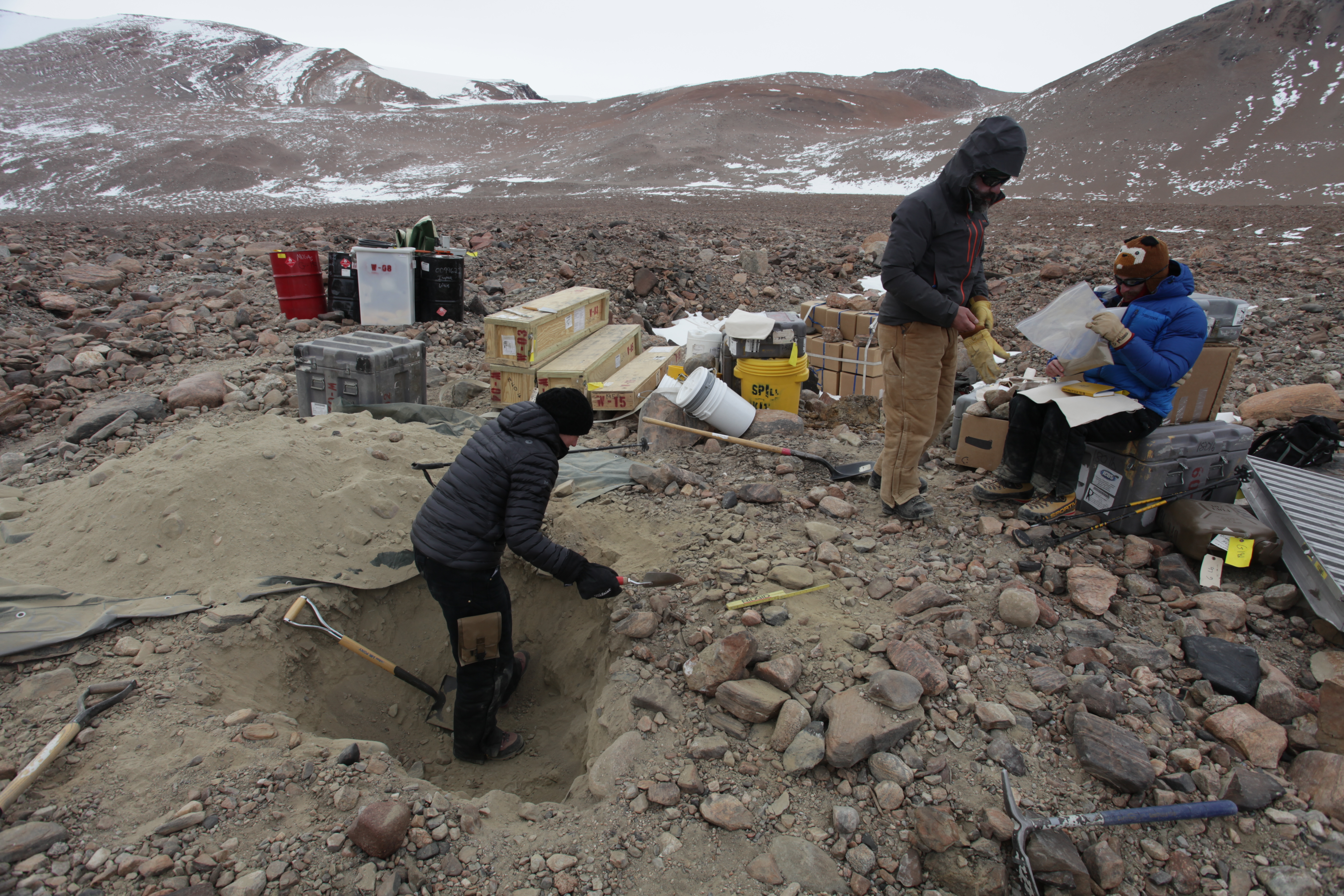 People digging in dirt and rocks in a valley.