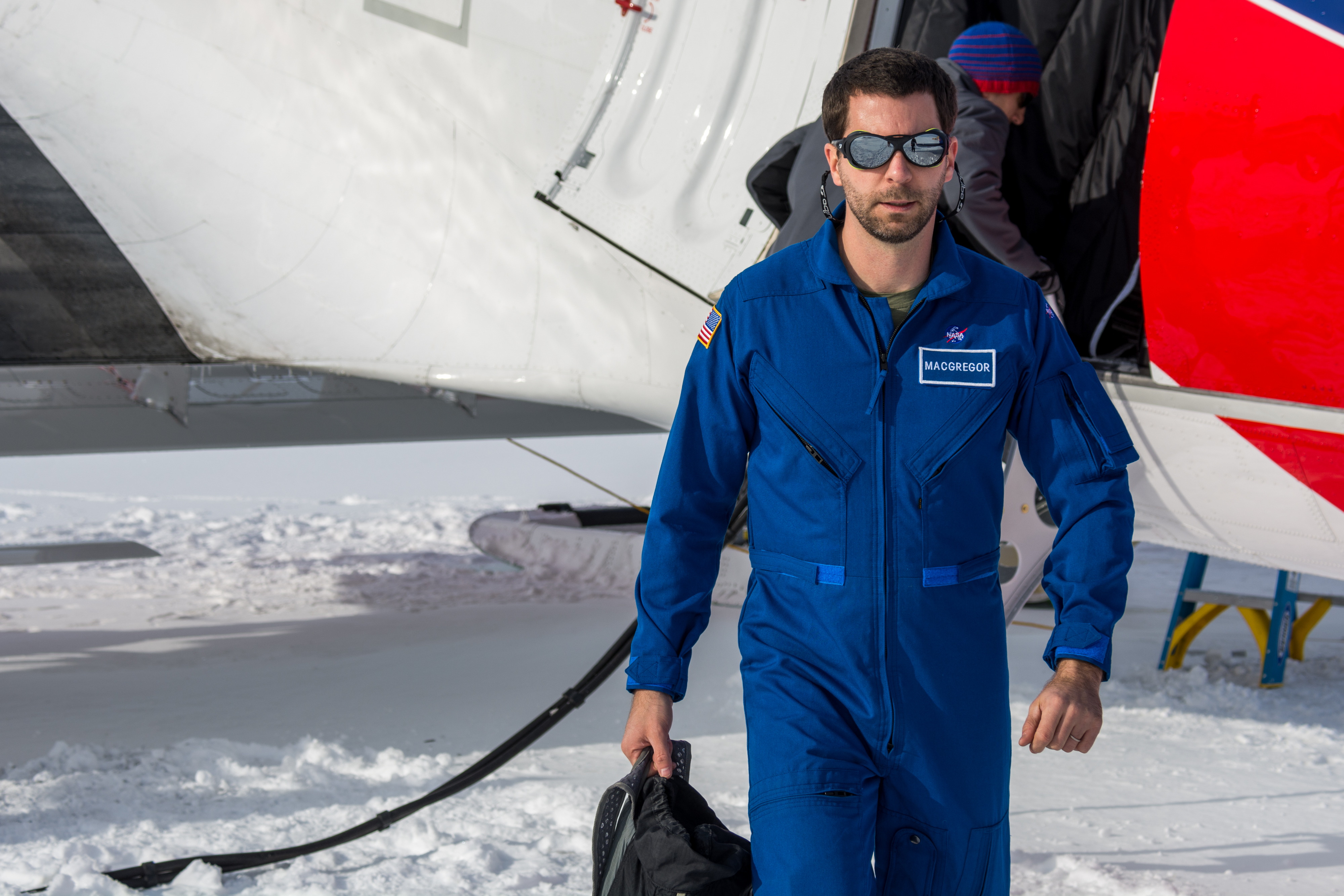 A man in a blue flight suit and sunglasses.