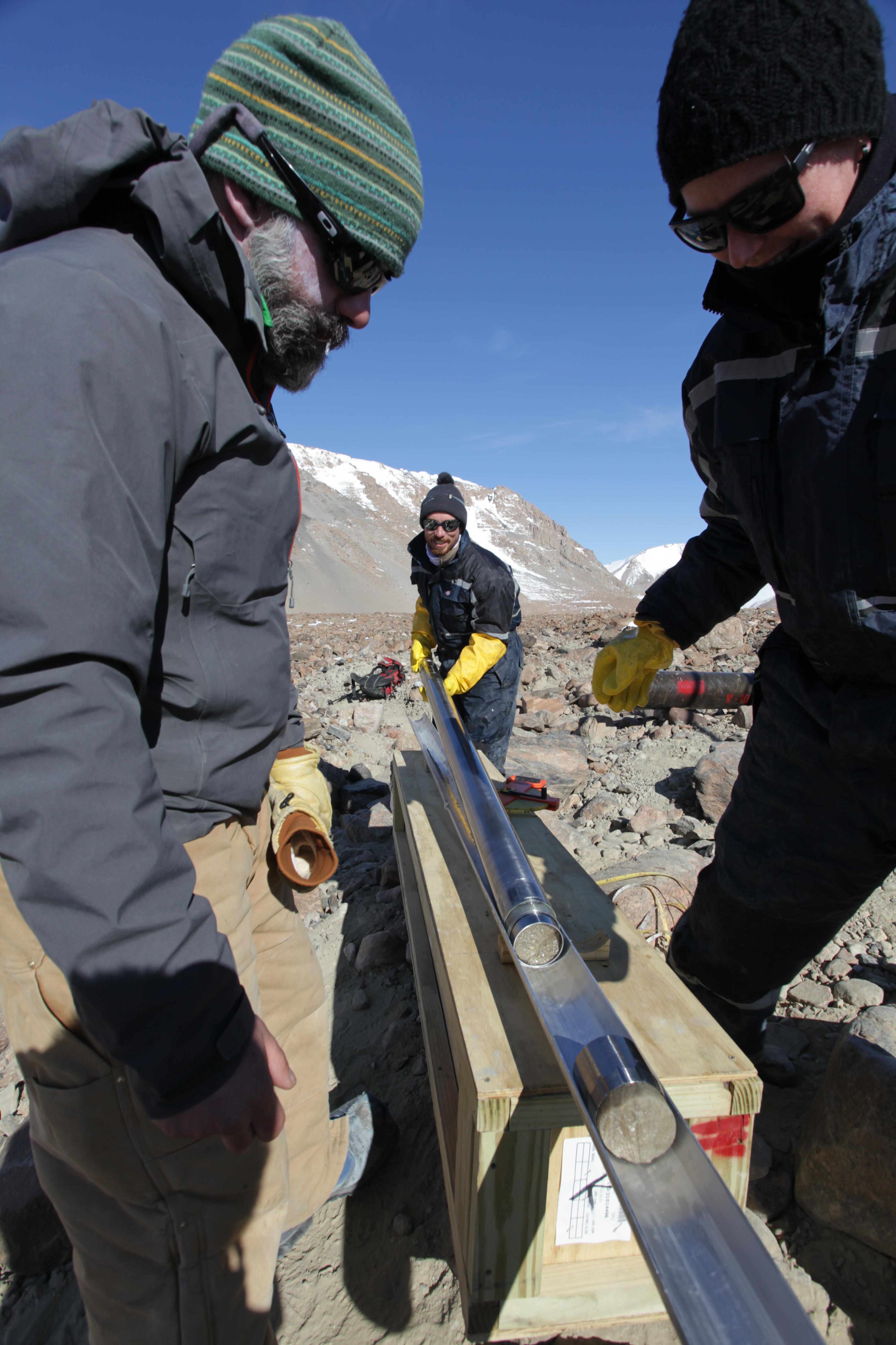 Three scientists extracting ice core samples.