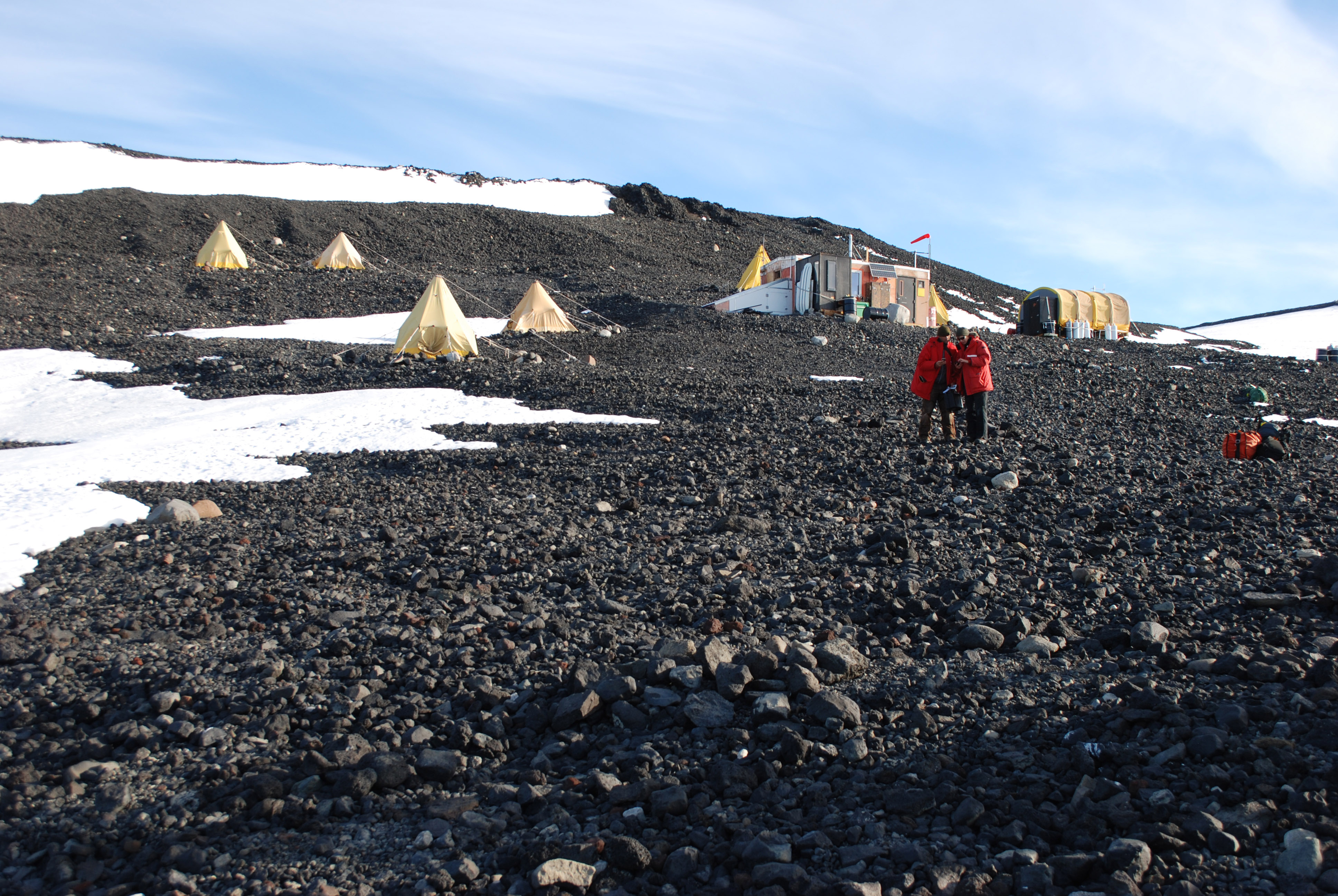 Yellow tents on a rocky hillside.