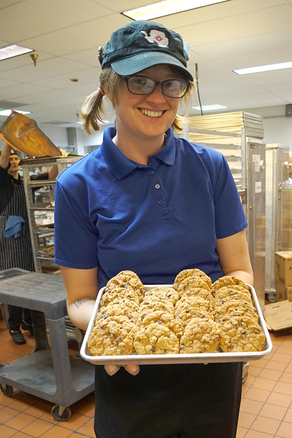 A woman holds a platter of cookies.