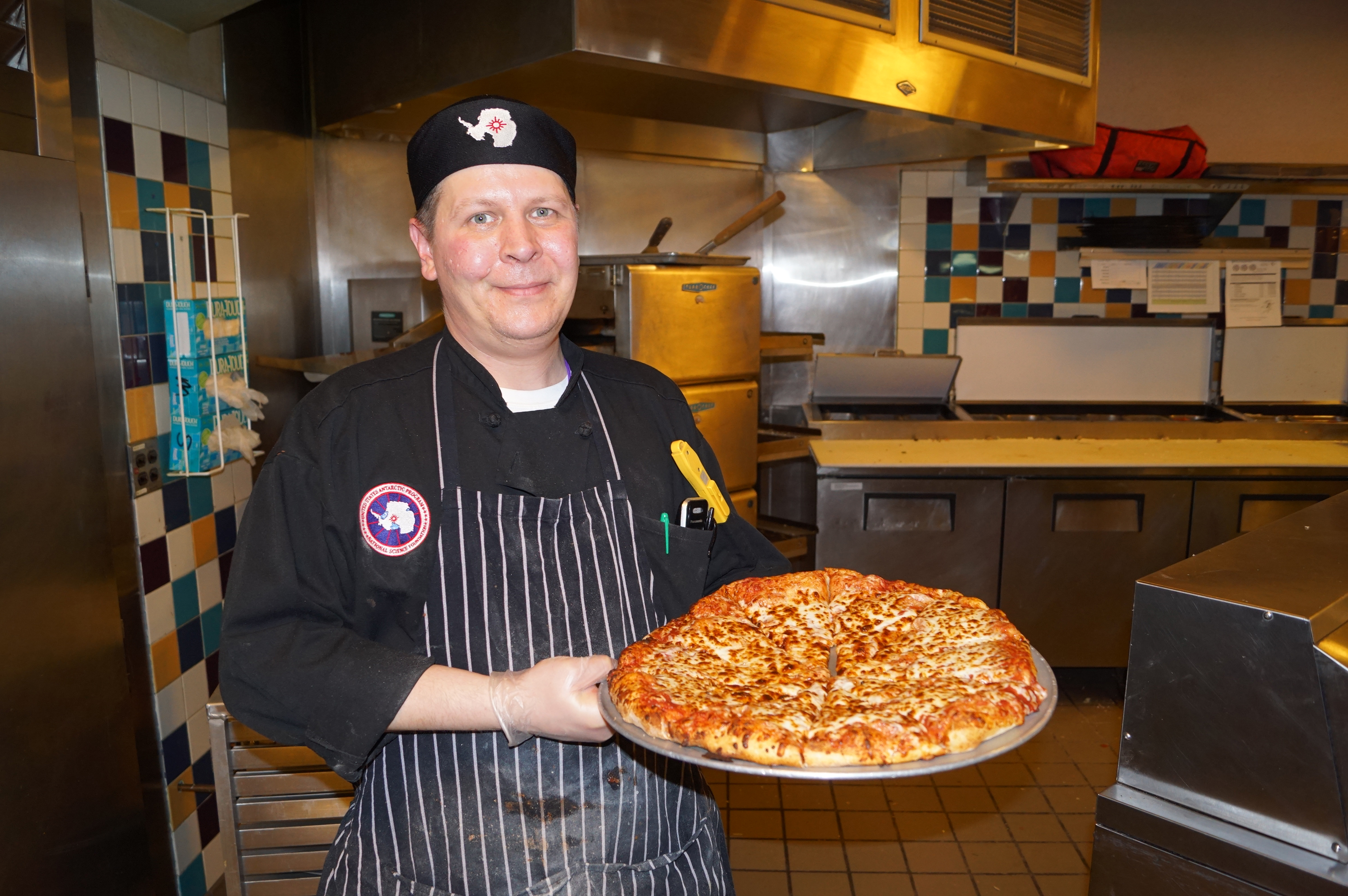 A cook holds a pizza.