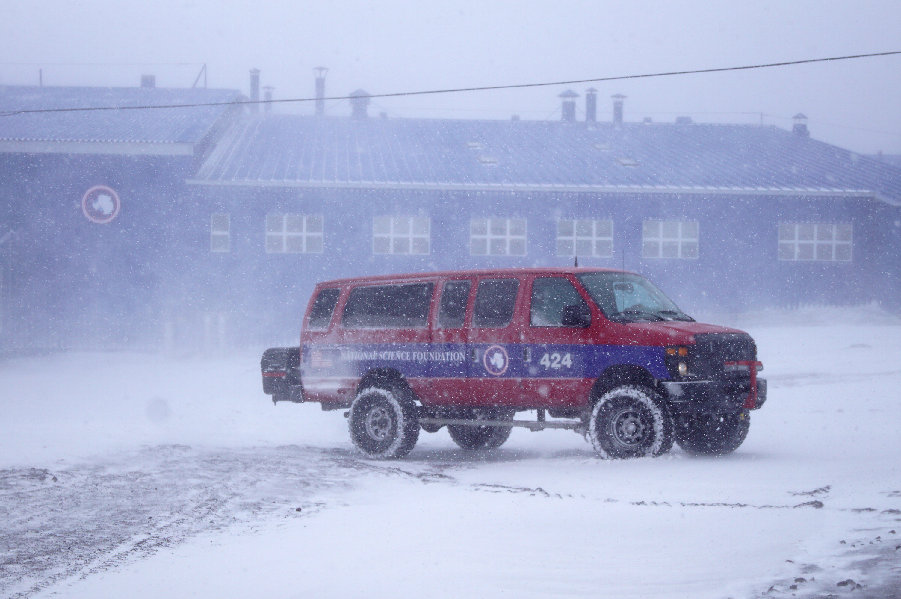 A red and blue van outside in stormy weather.