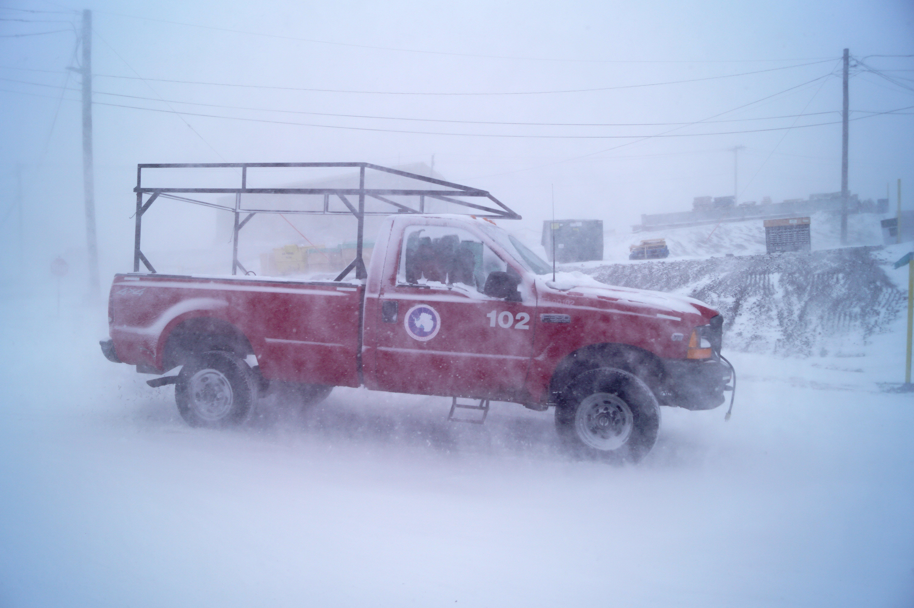A red pickup truck in snowy weather.