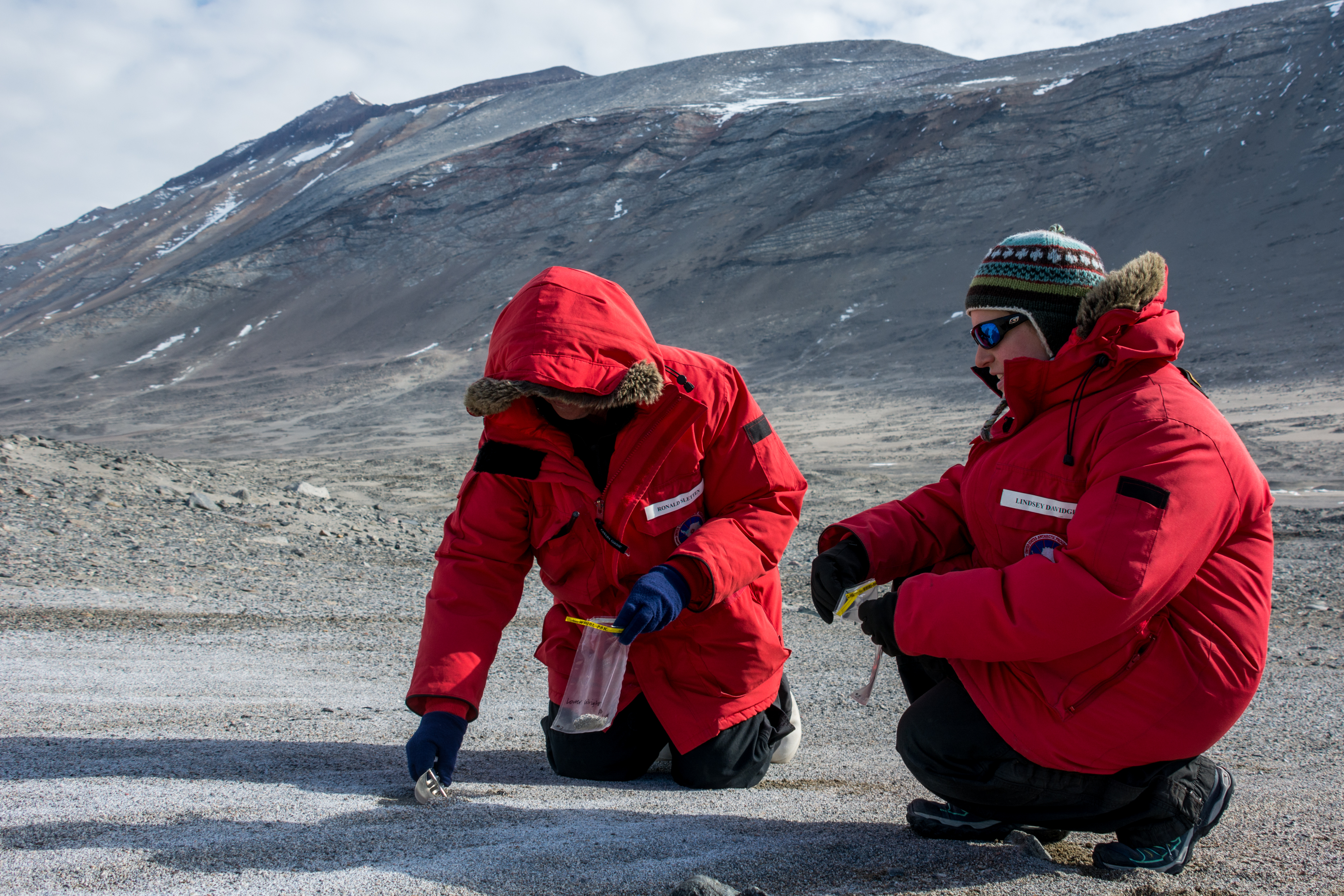 Two people in red parkas taking soil samples.