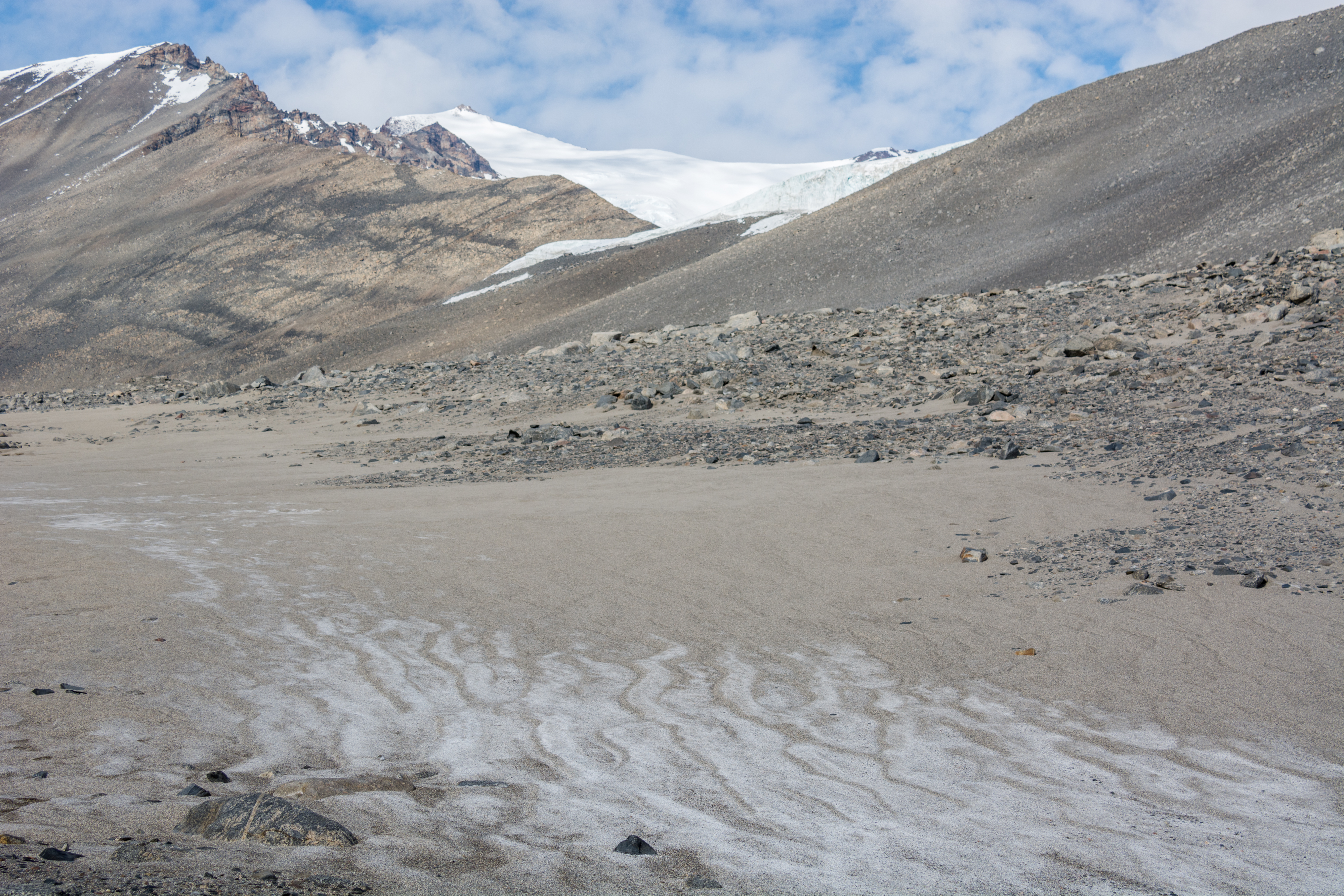 A view of salt deposits in the landscape and mountains in the background.