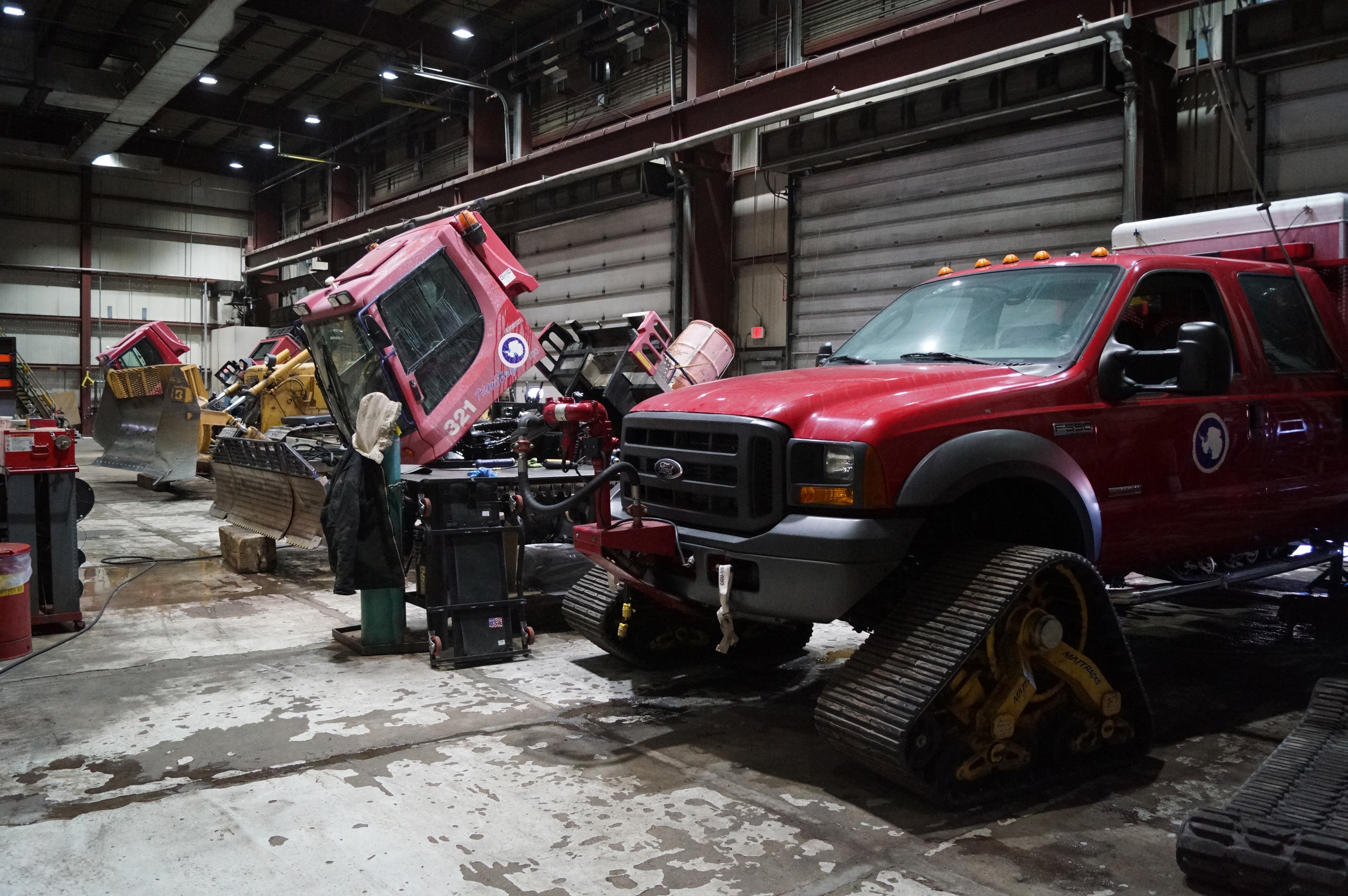 Several large vehicles inside a garage for mechanics.