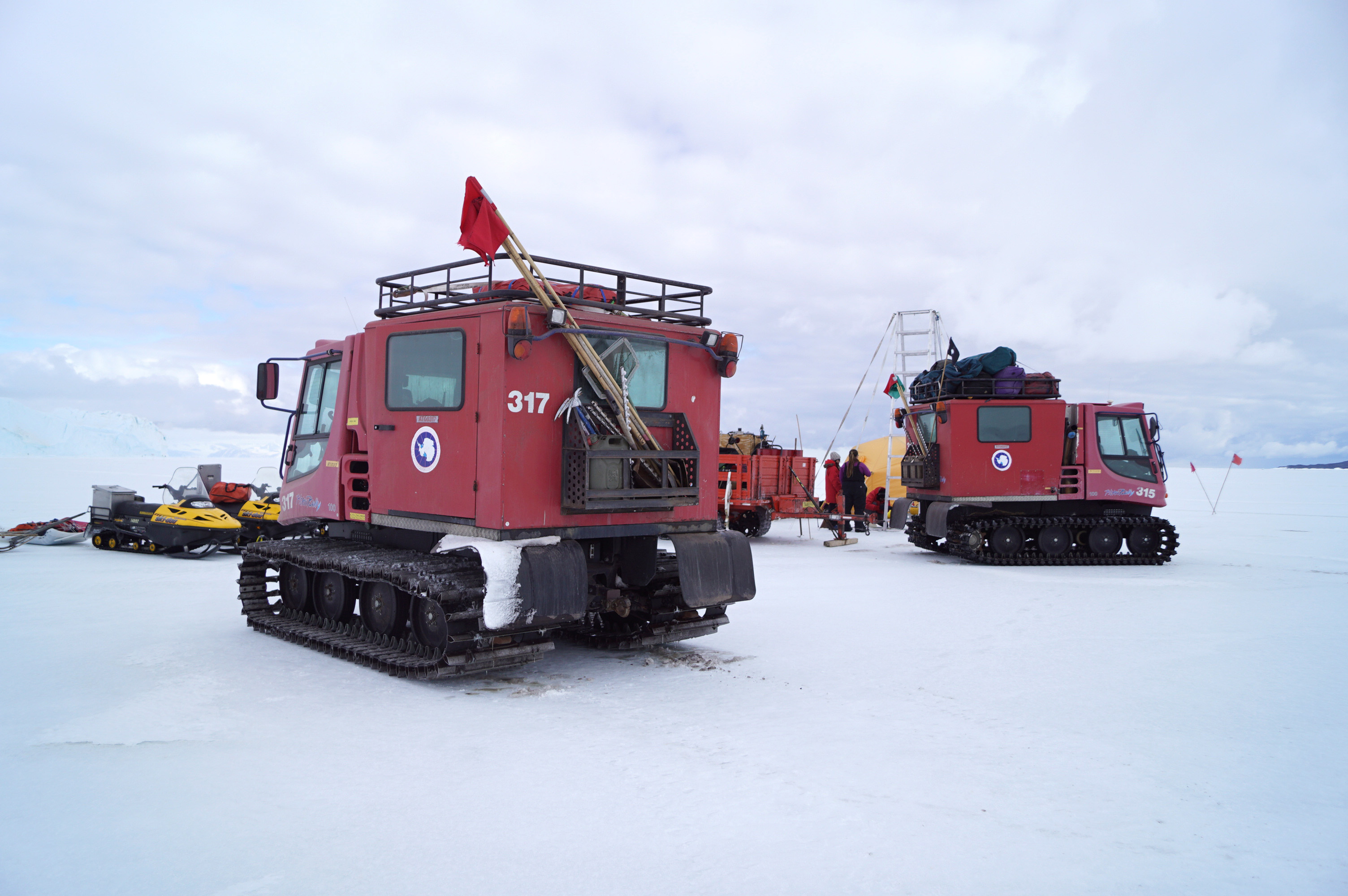 Two red tracked vehicles parked on ice.