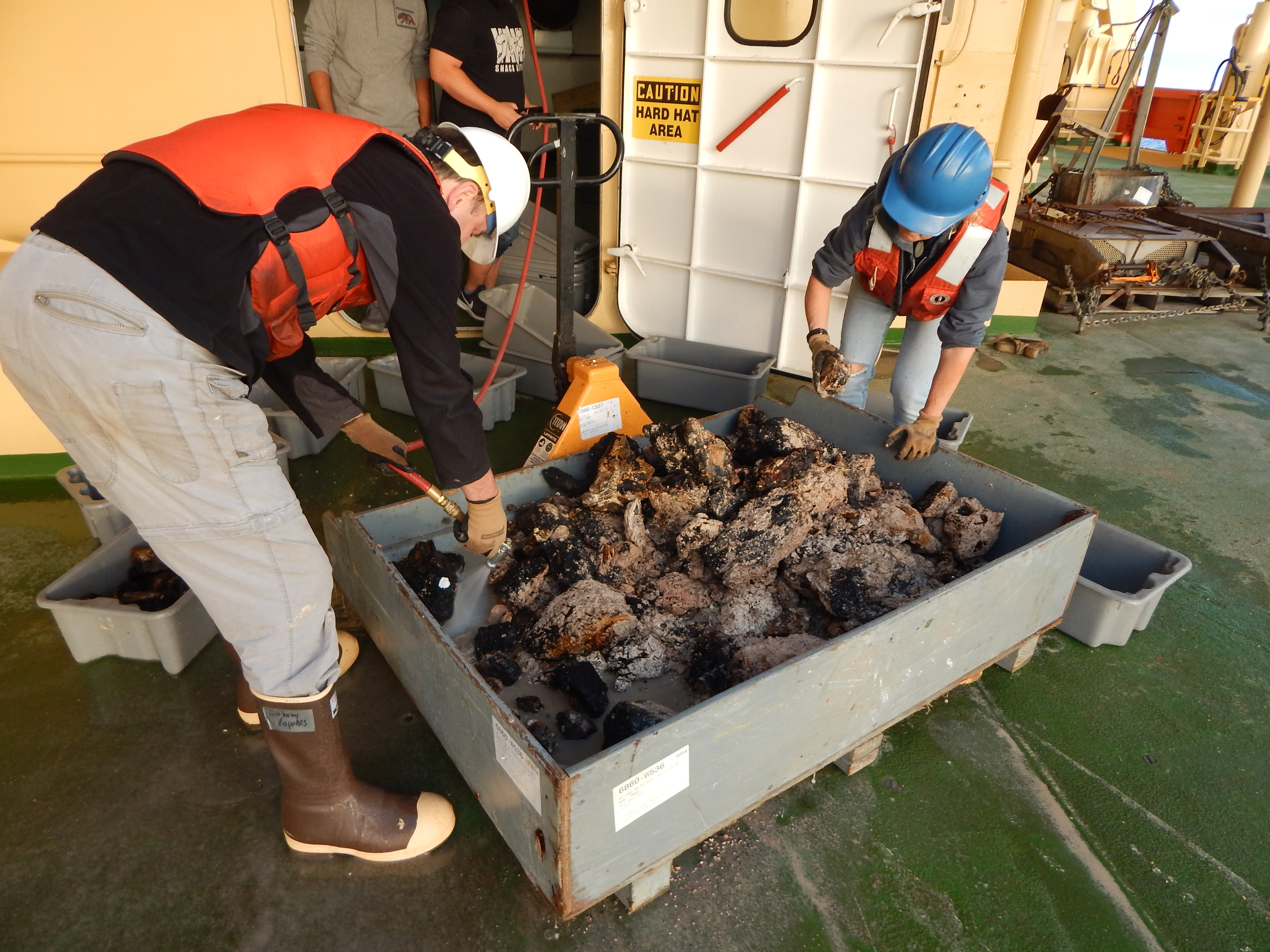 People working with large rocks in a large box.