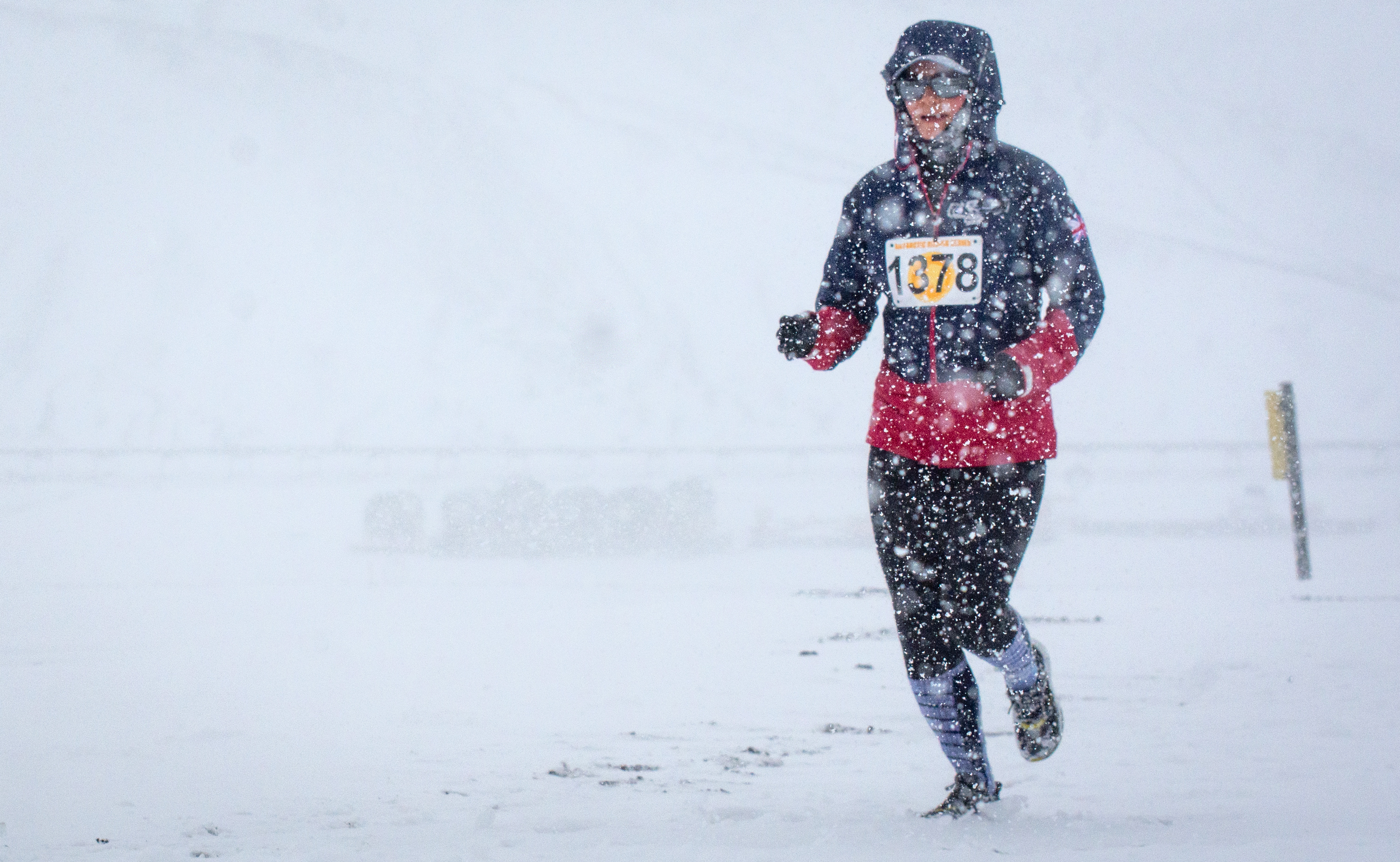 A person runs a race in a snowstorm.