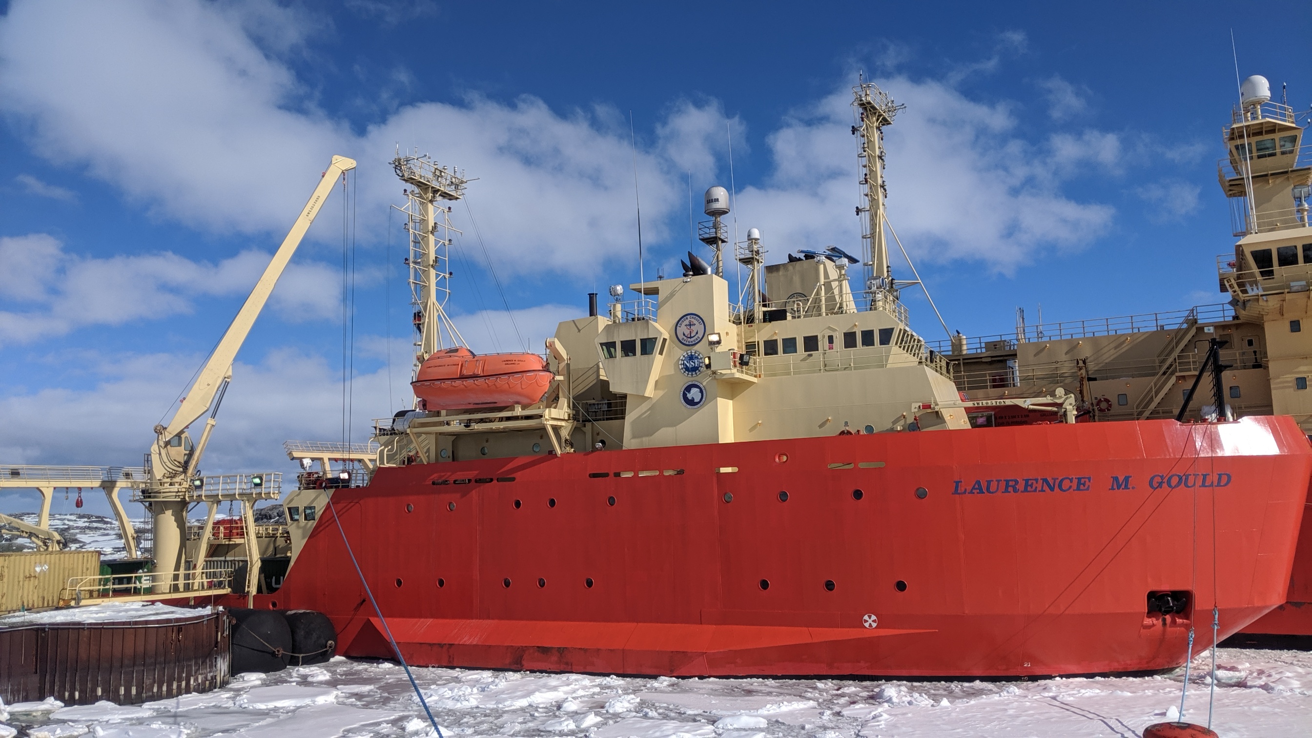 A ship in icy waters with another ship close behind it.