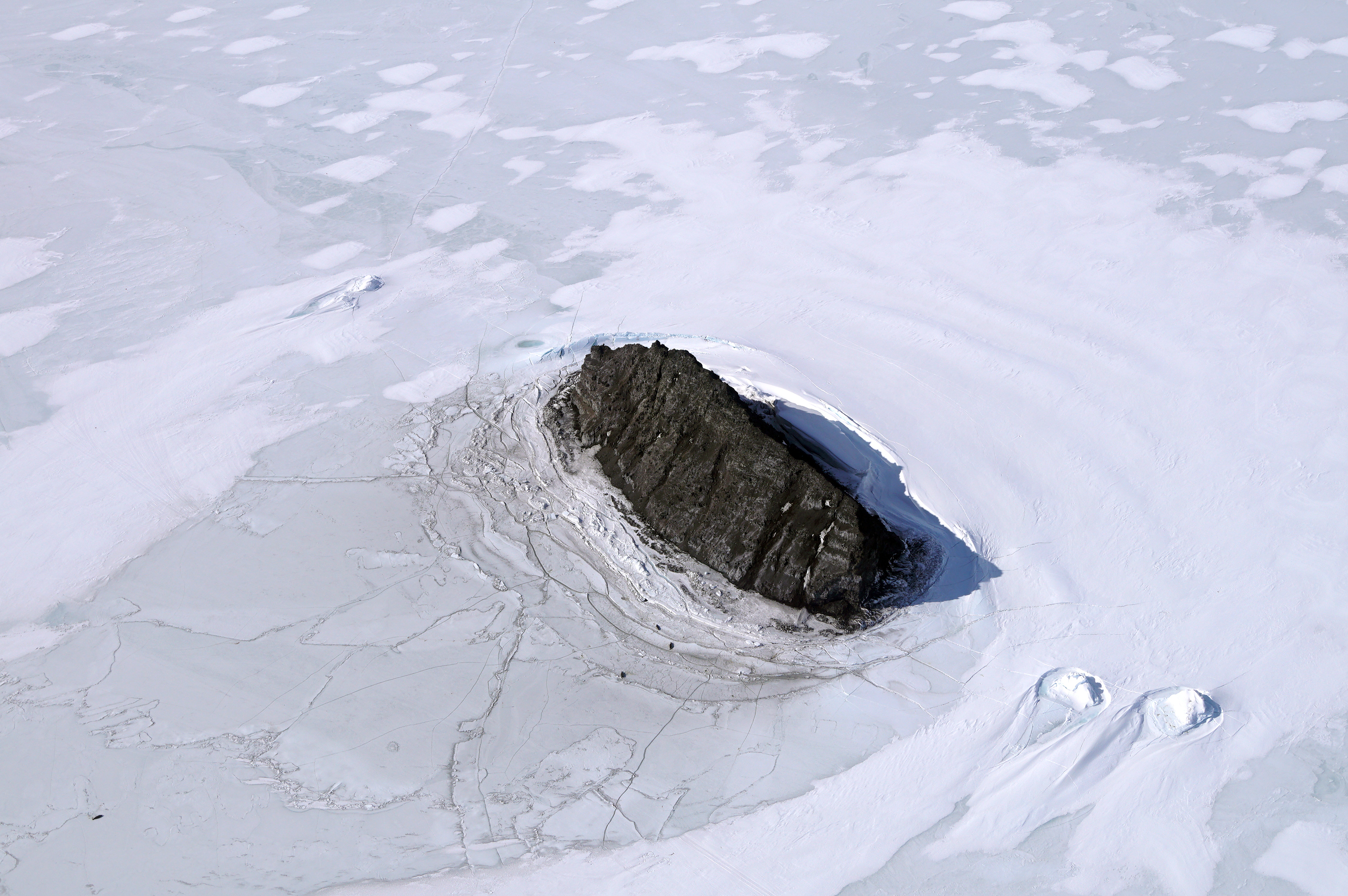 Aerial view of a rock island surrounded by ice.