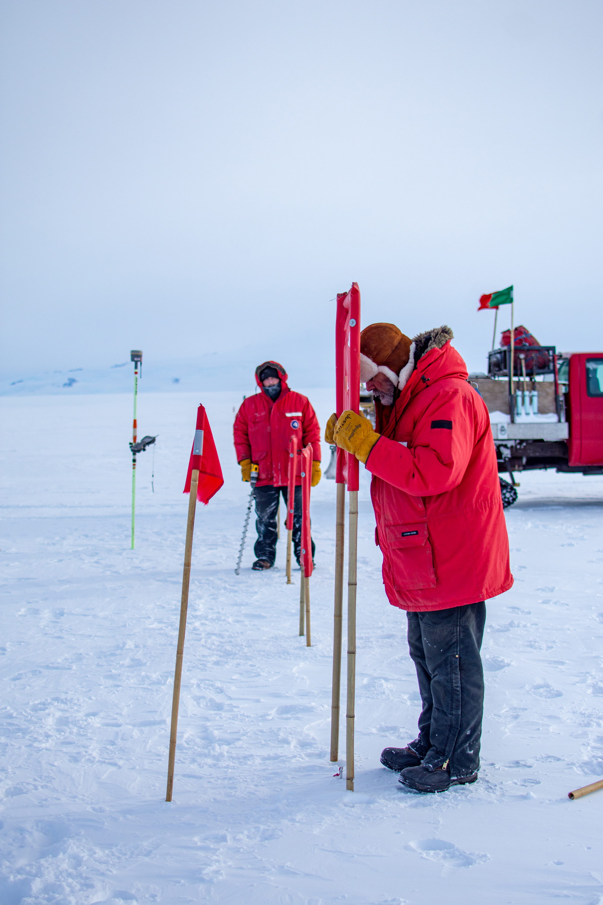 Two people in winter clothing placing airfield markers.