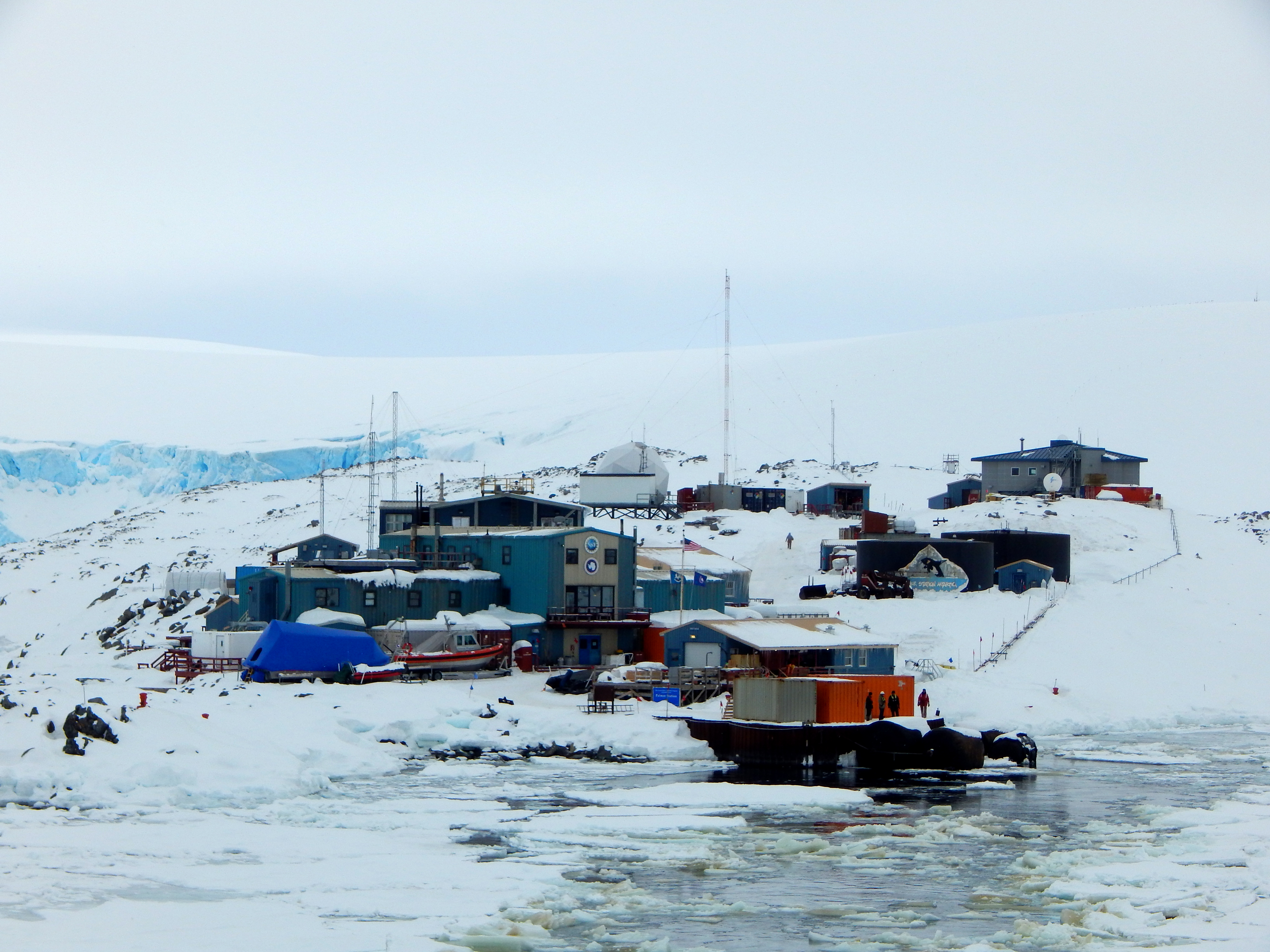 A few buildings along a snow-covered coastline.