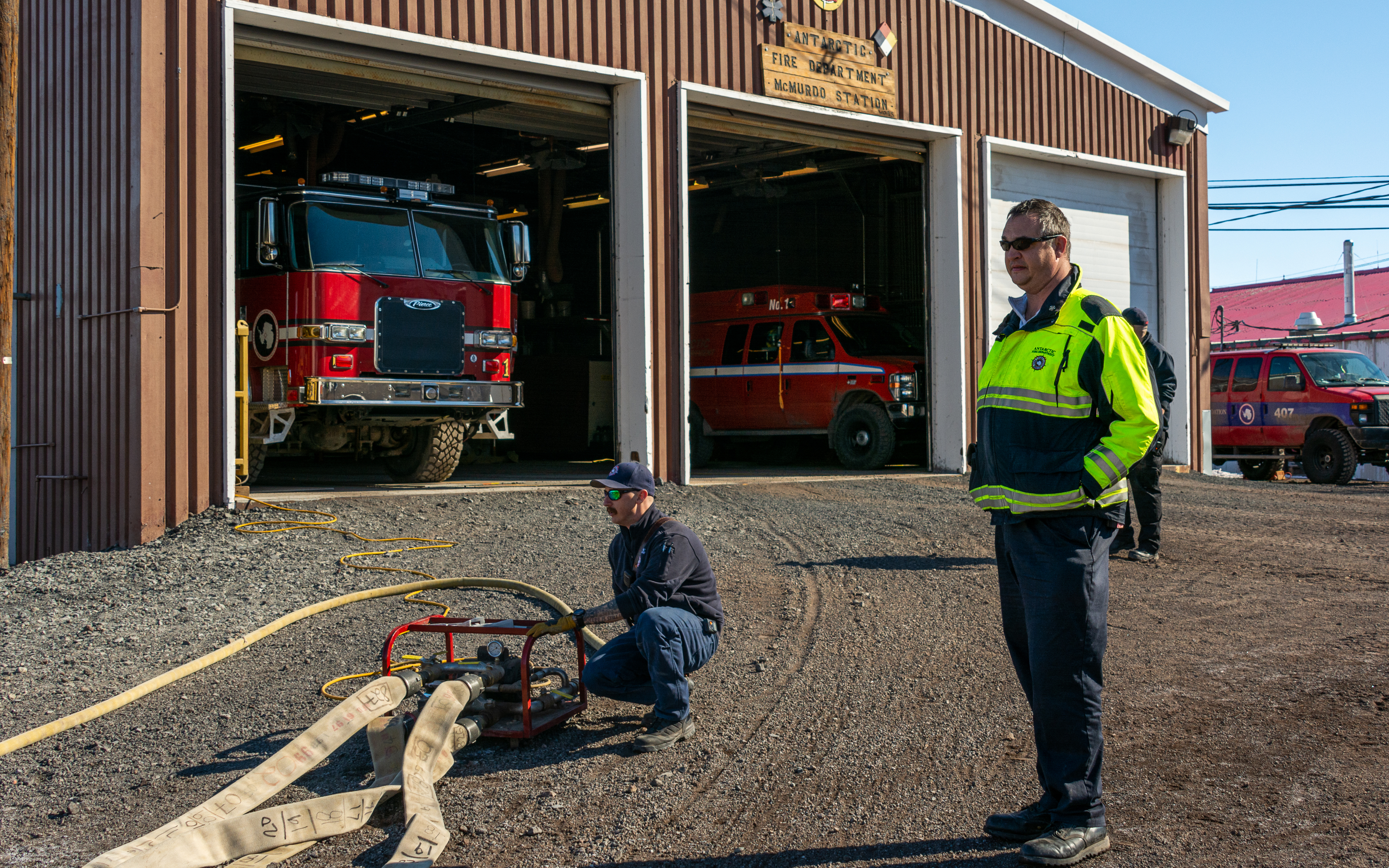 Two firefighters in front of a fire station.