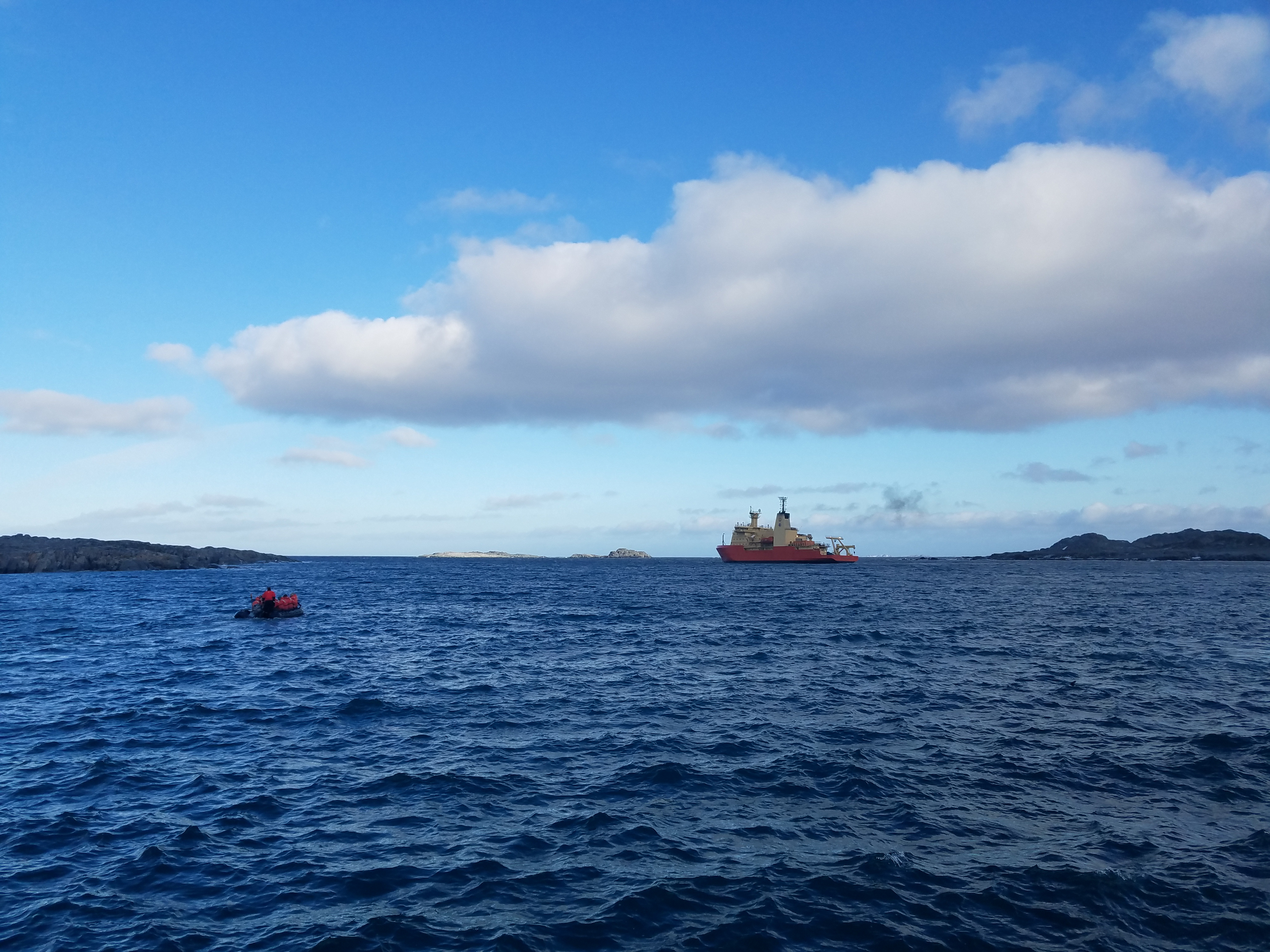 A small boat approaches a ship in the ocean.