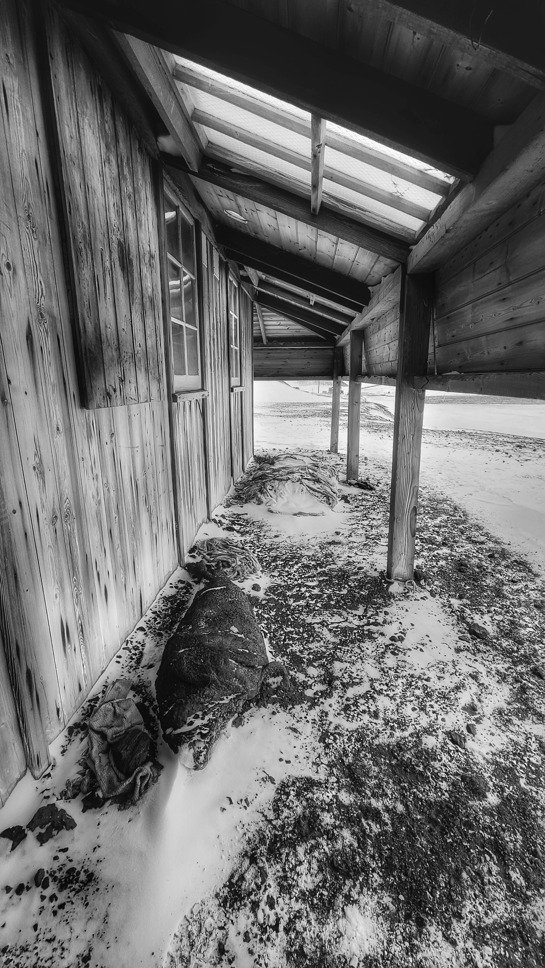 A black and white photo of the exterior of a wooden building with an awning.