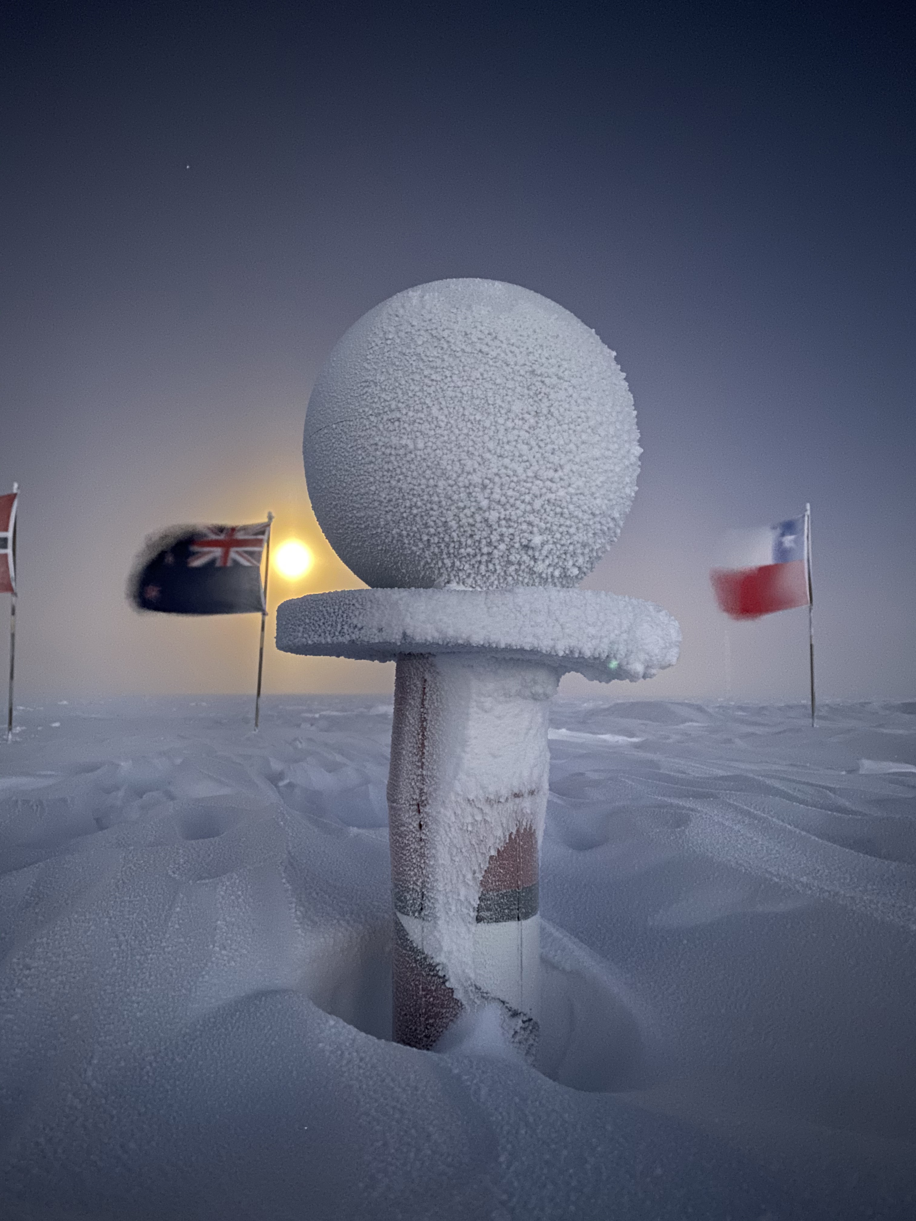 A snow-covered sphere on top of a post.