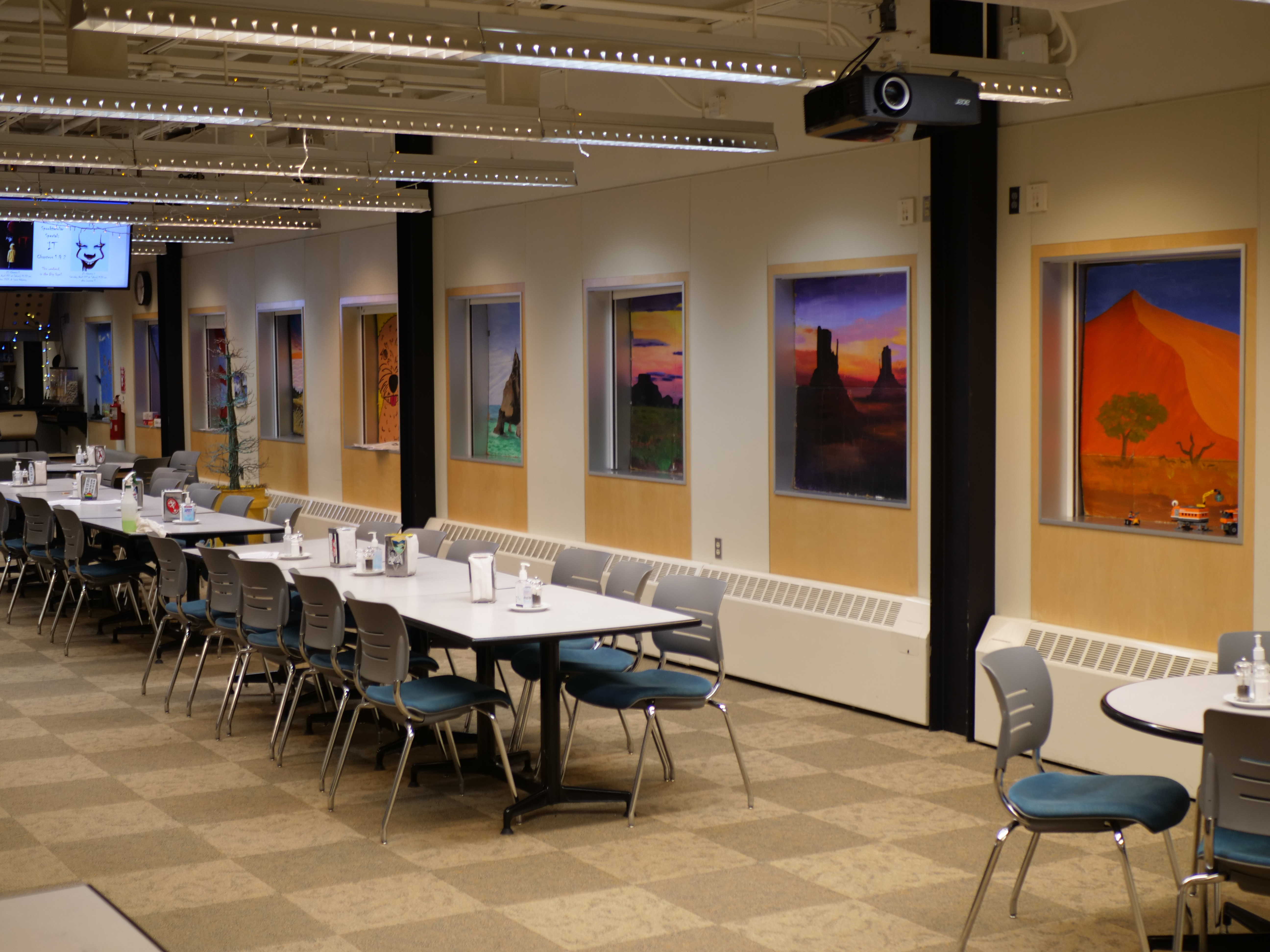 A dining room with colorful paintings on the wall.