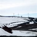 Three wind turbines and a satellite dish on top of a hill.
