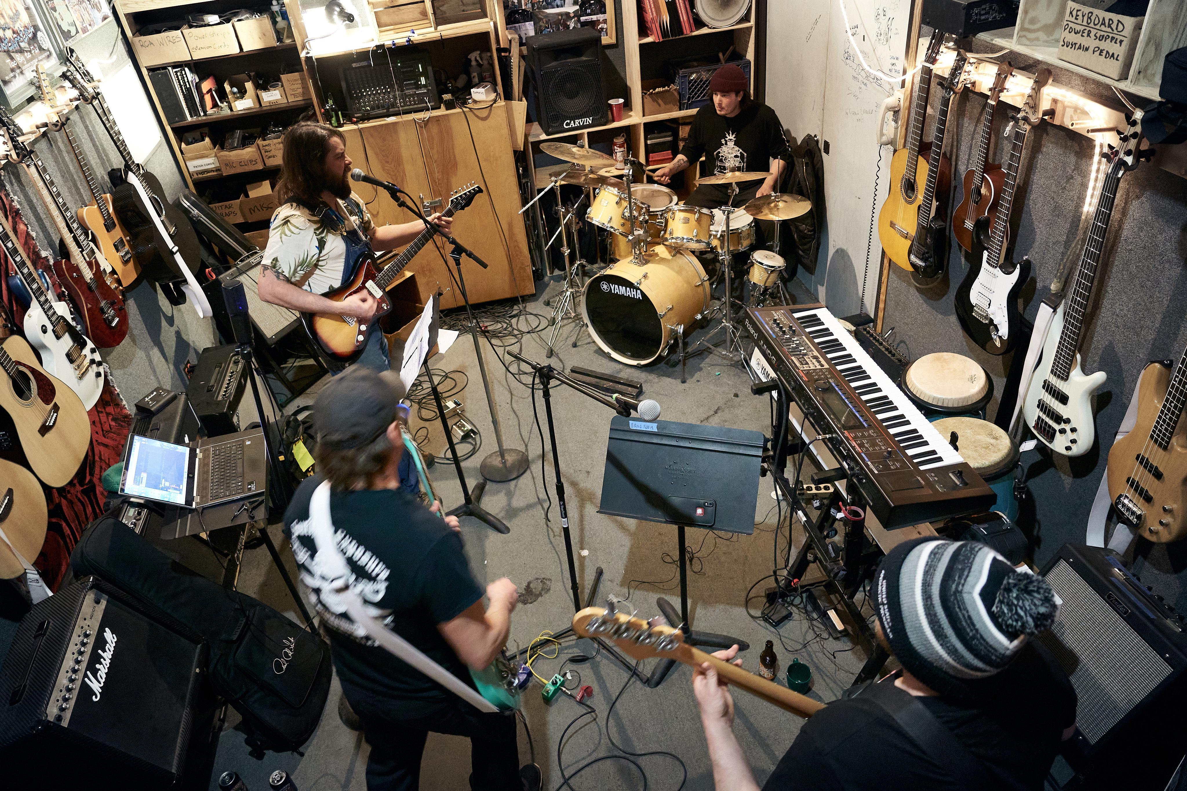 Four members of a band are practicing in a small room.