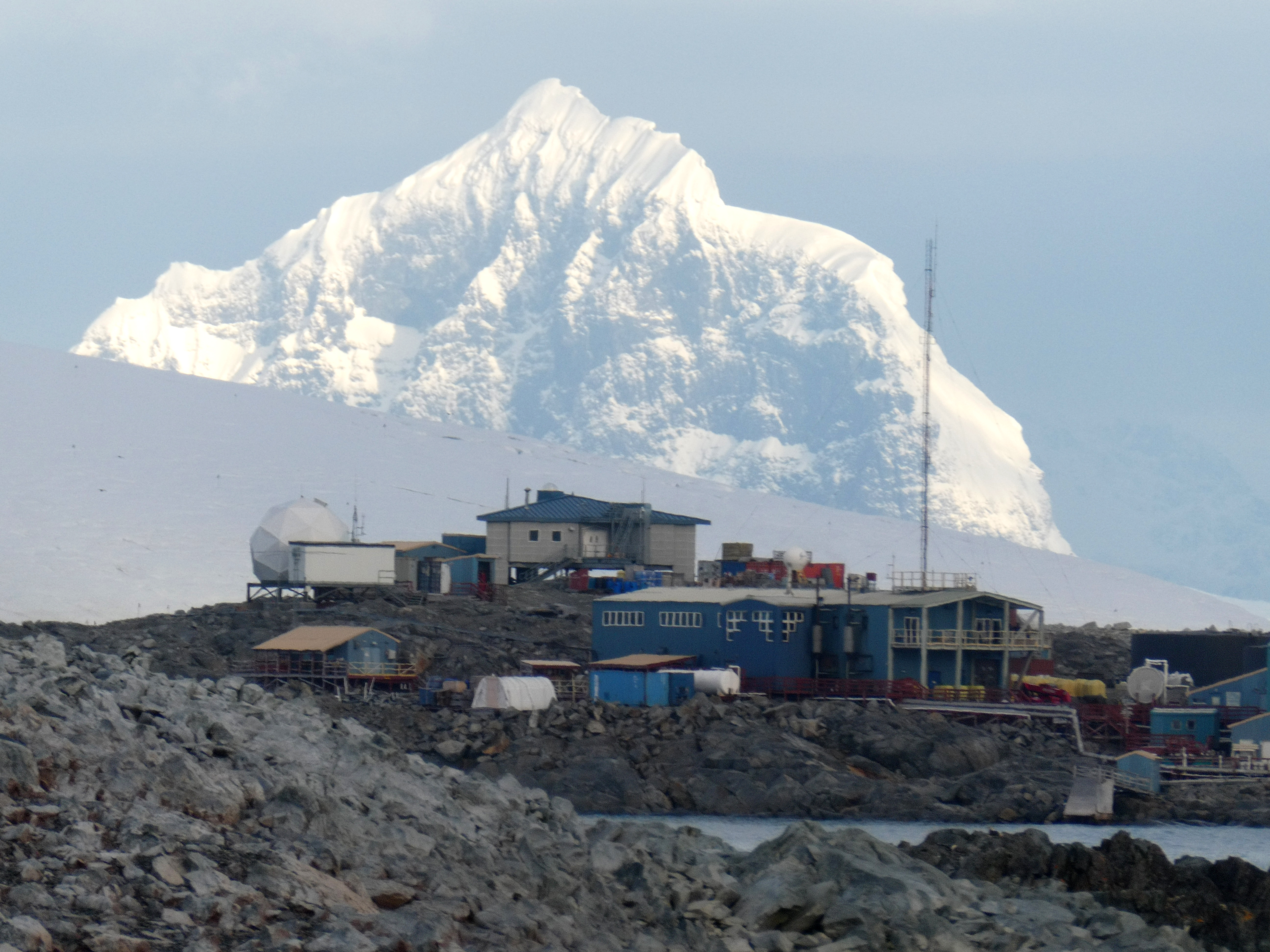 A snow-covered mountain looms high behind a cluster of buildings.