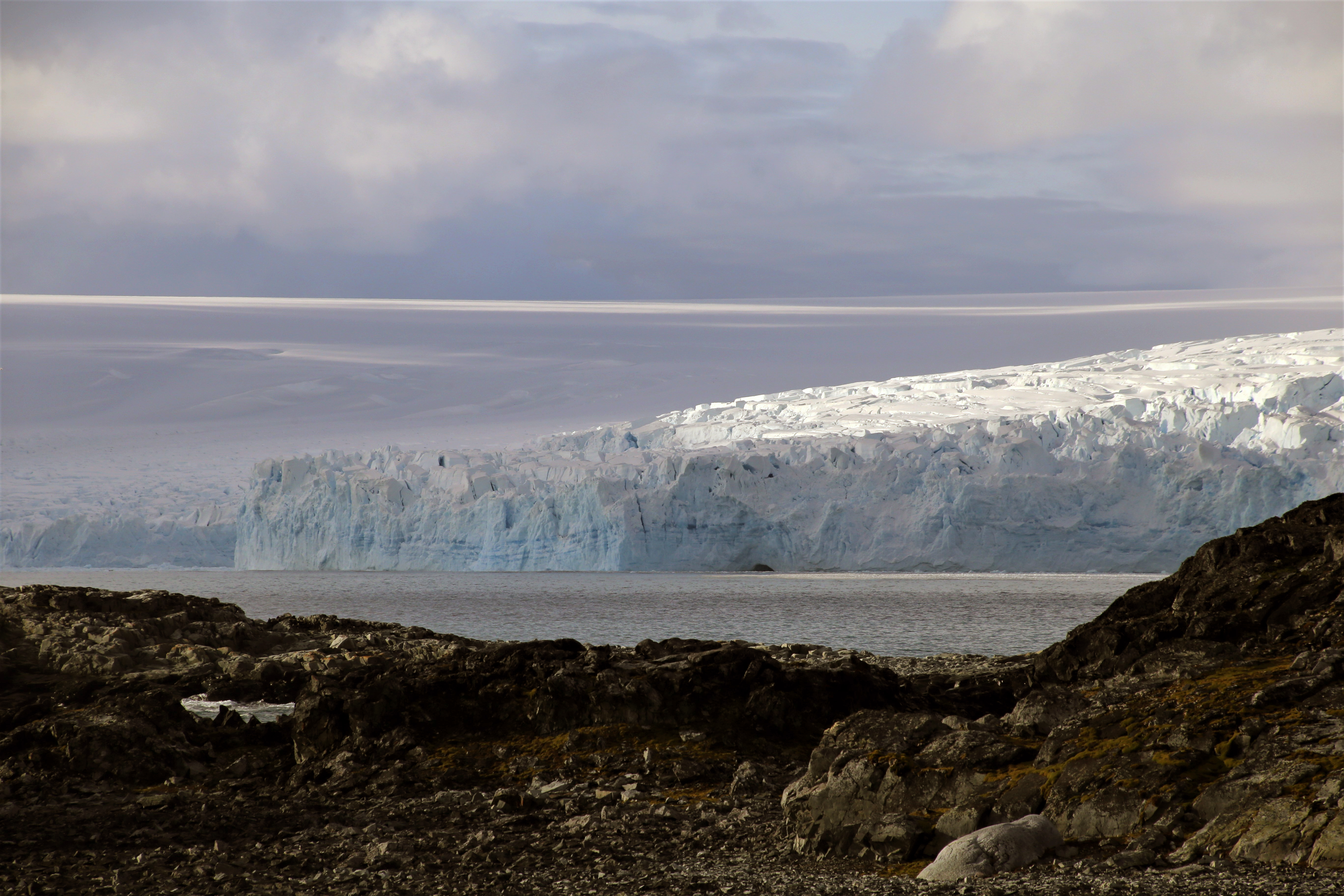 A glacier in the distance and rocky bare land in the foreground.