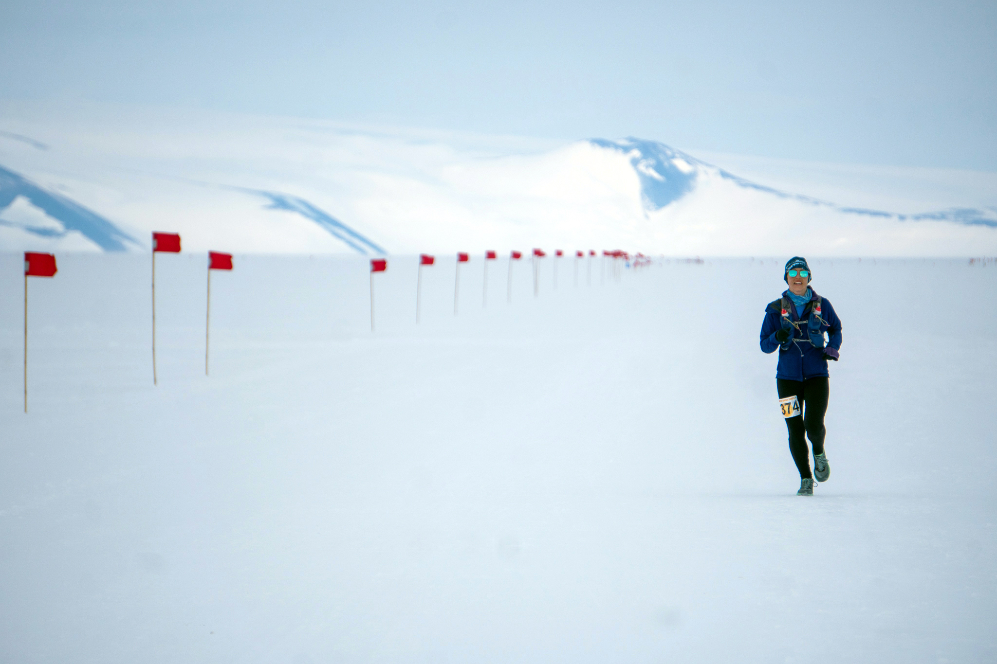 A person running in a race along a flagged snowy route.